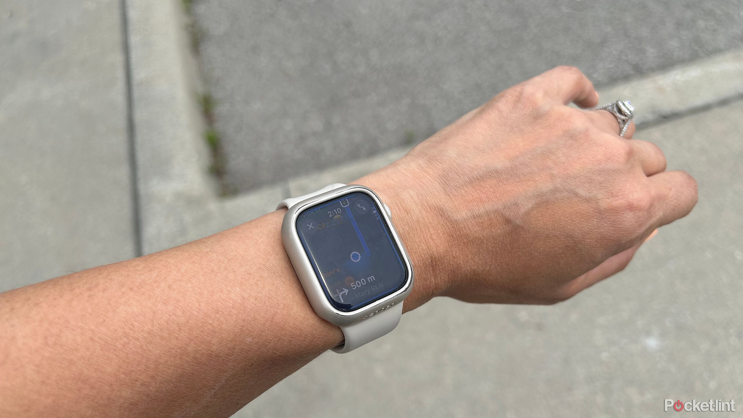 An Apple Watch on a wrist outside showing turn by turn navigation directions from Apple Maps