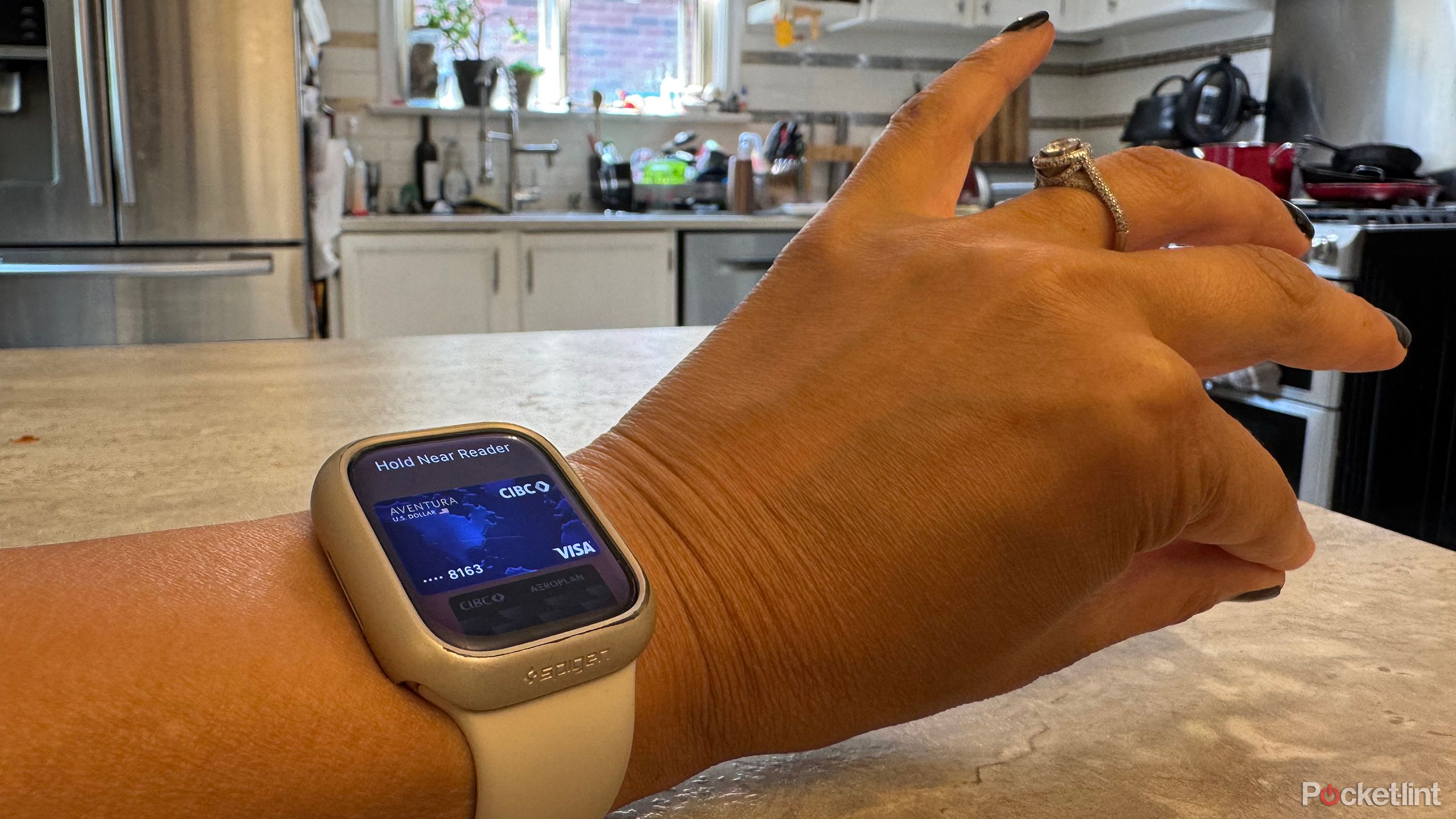 An Apple Watch on a wrist showing Apple Wallet cards with two fingers pinching together.