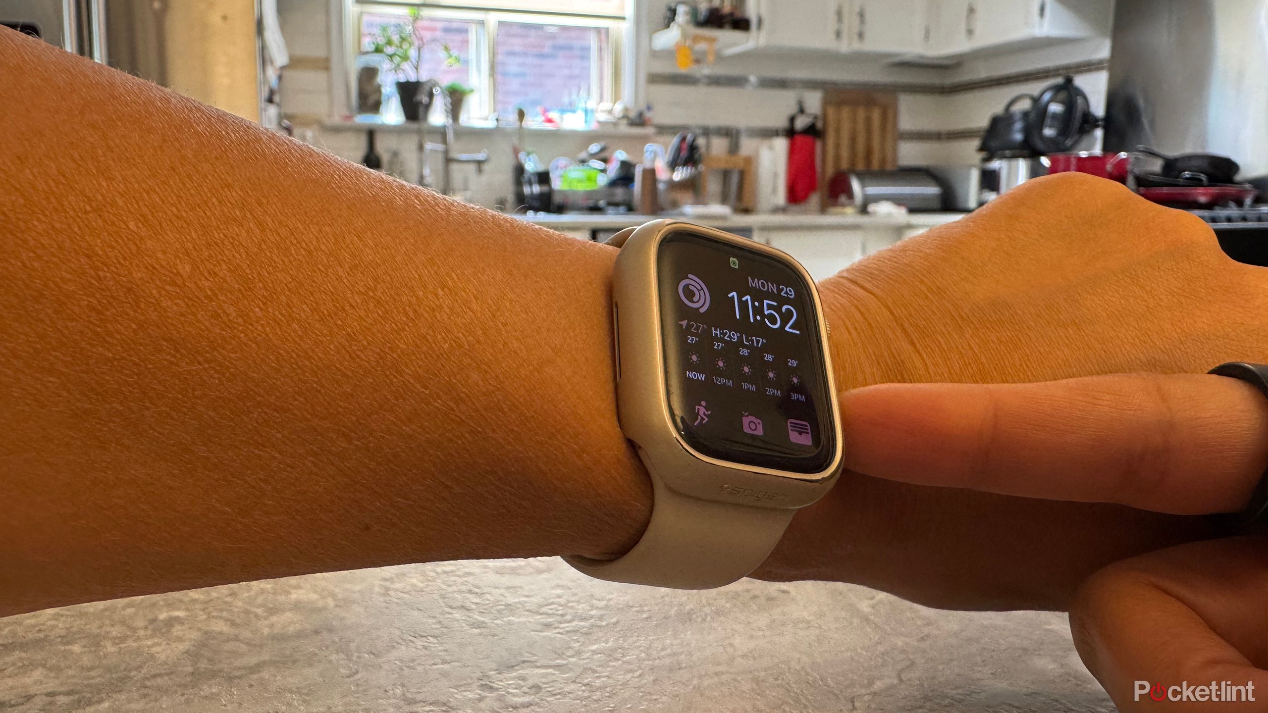 An Apple Watch on a wrist with a finger touching the side button.