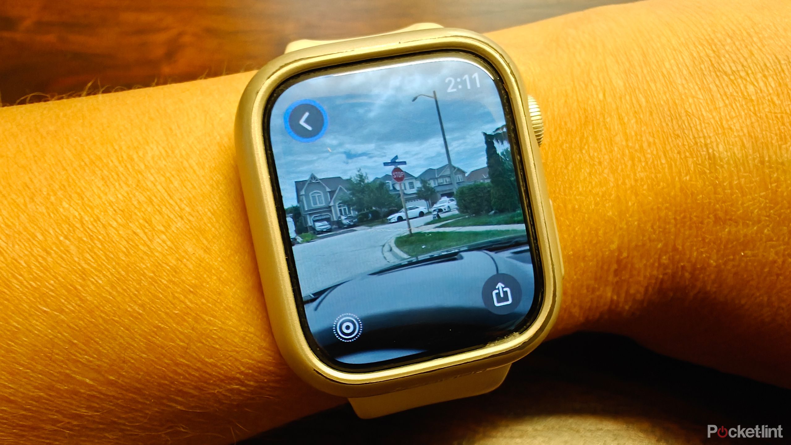 An Apple Watch on a wrist showing an image of street signs on the road.