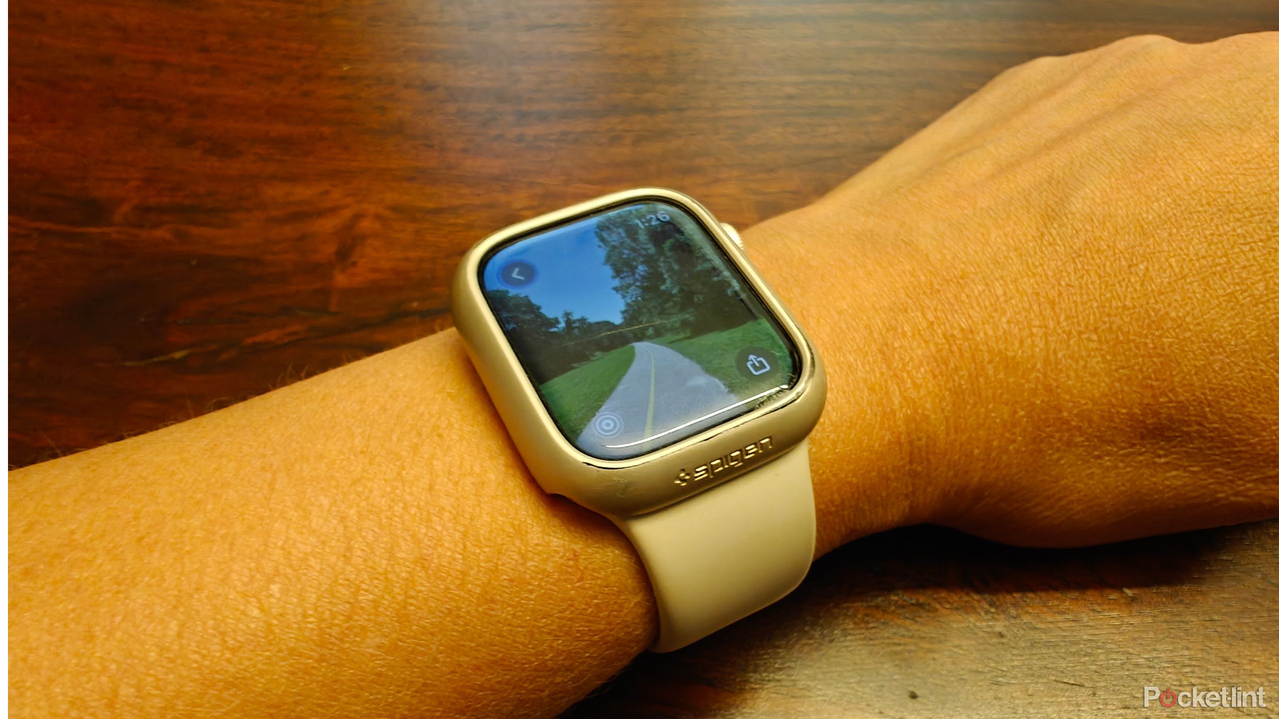 An Apple Watch on a wrist showing an image of a trail.