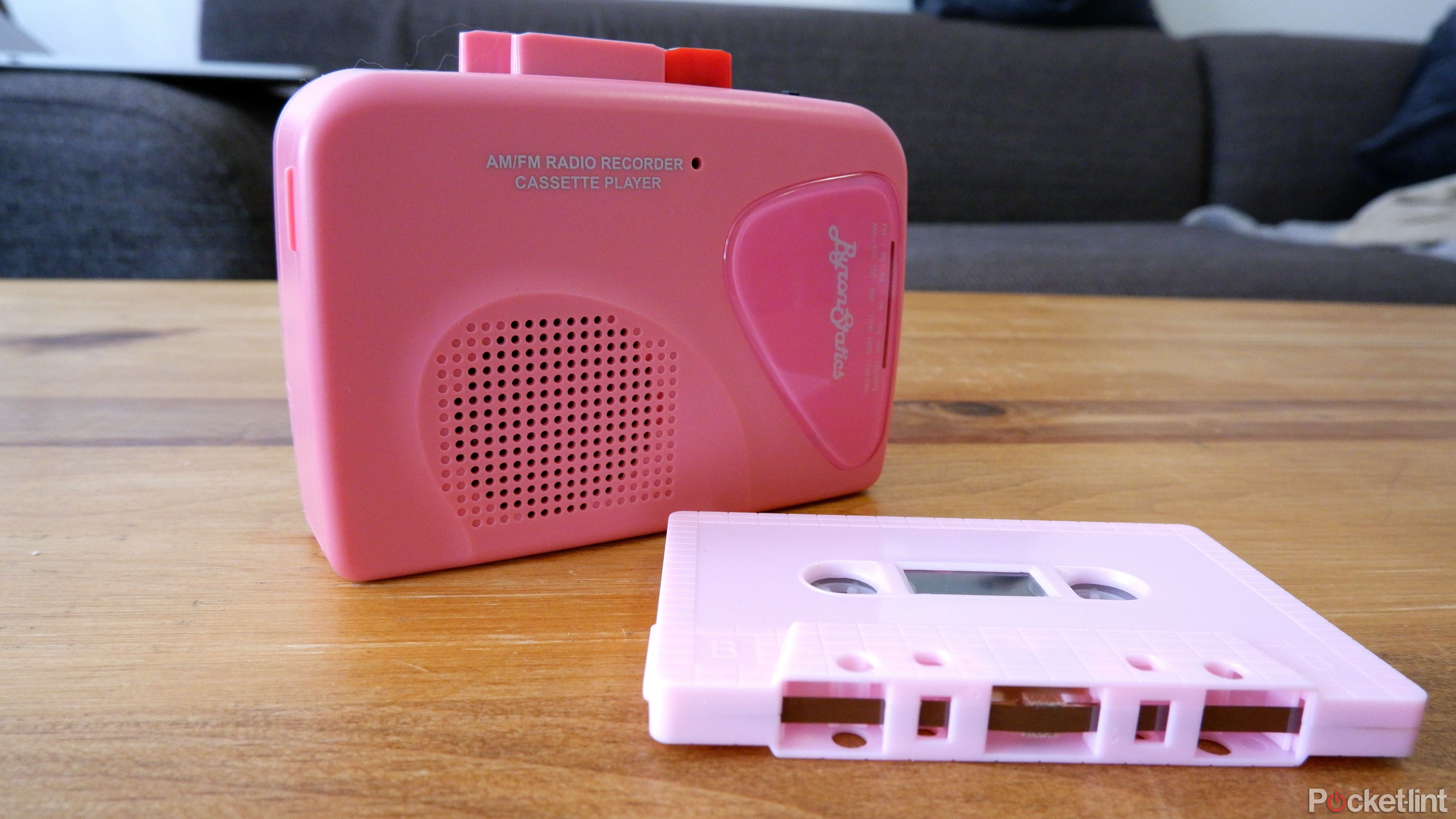 A ByronStatics cassette player on a wooden coffee table next to a pink cassette tape