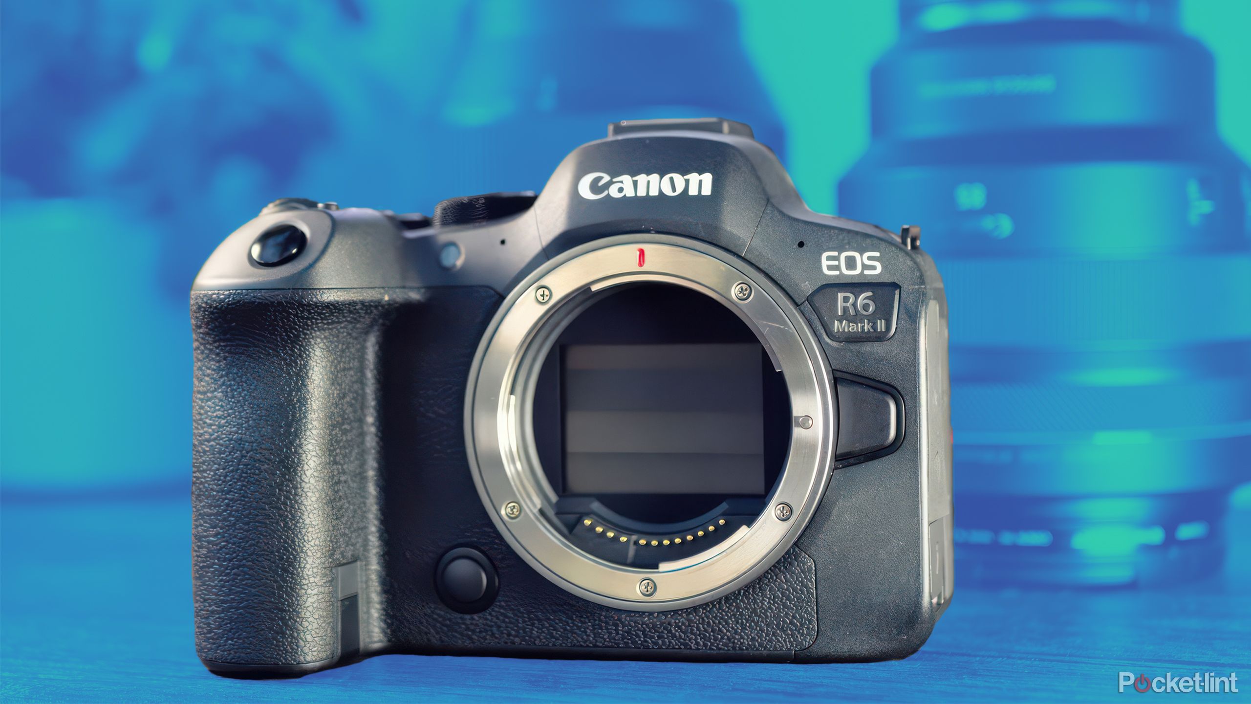 The Canon R6 Mark II in front of blurred out lenses that are in a blue-green gradient.