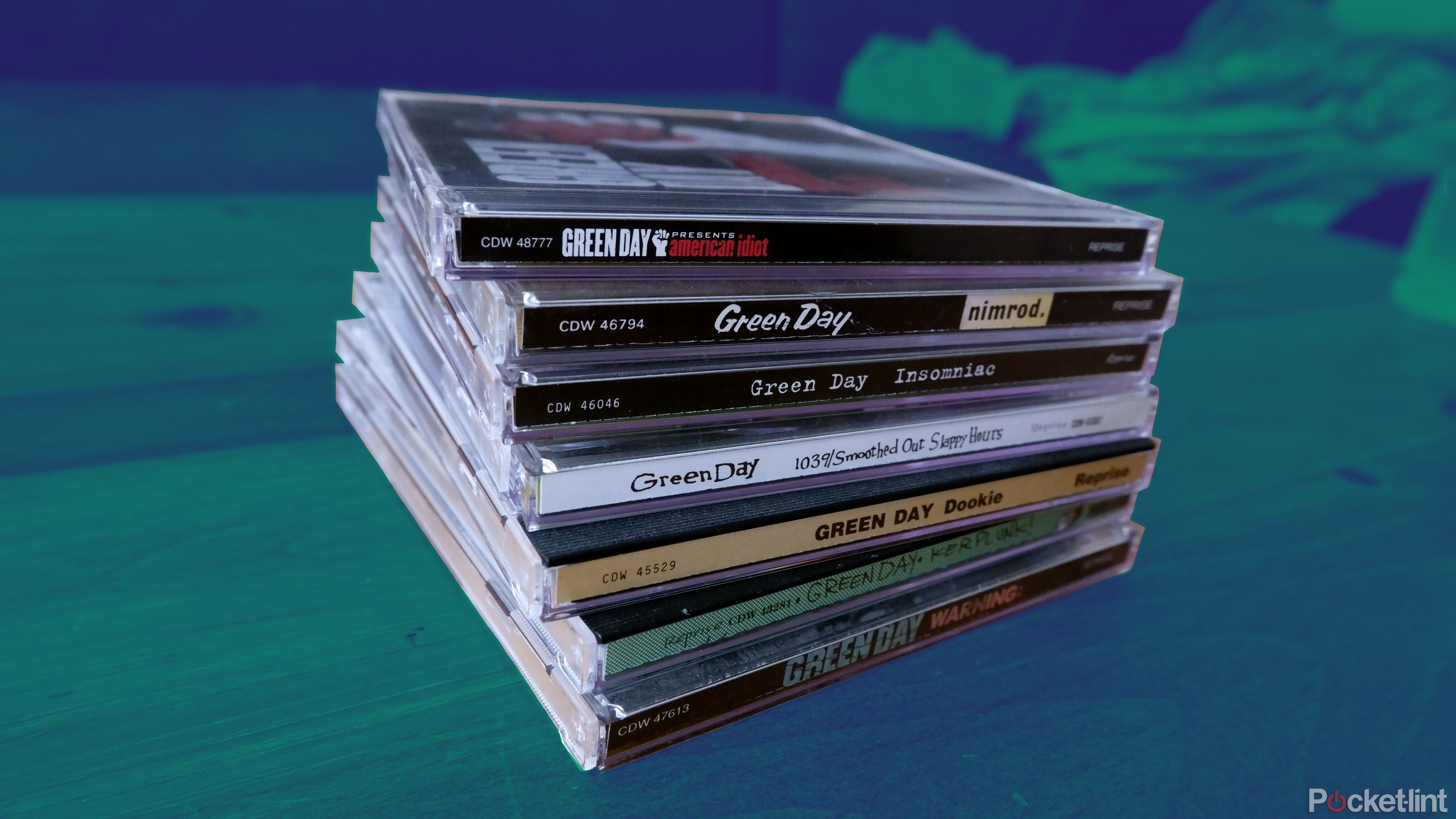 A stack of Green Day CDs on a coffee table