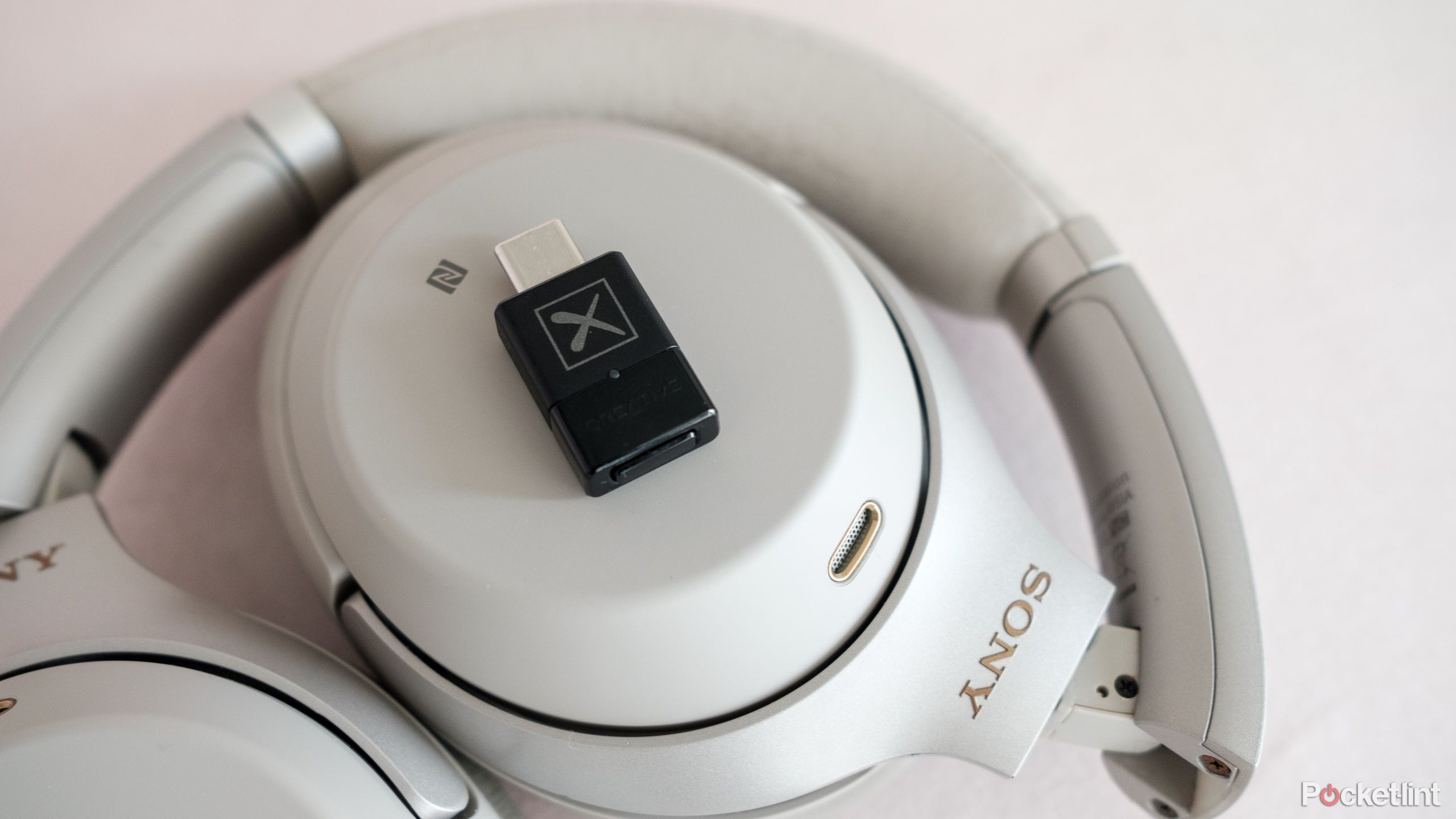 The Creative BT-W5 sits on a pair of Sony WH-1000XM3 headphones