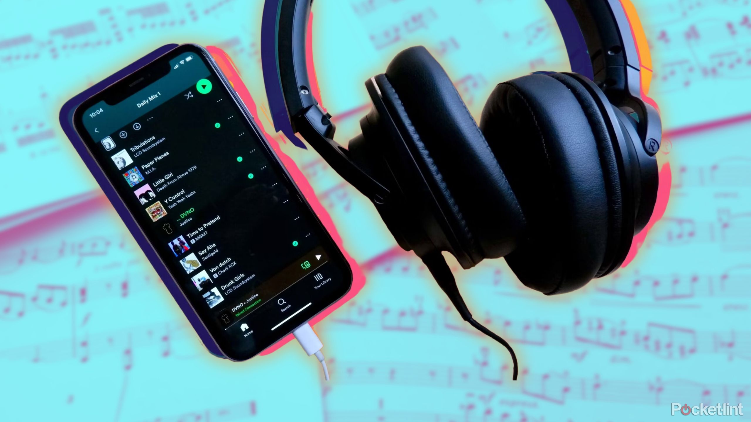 An iPhone with Spotify open with a pair of headphones plugged in against music sheets.