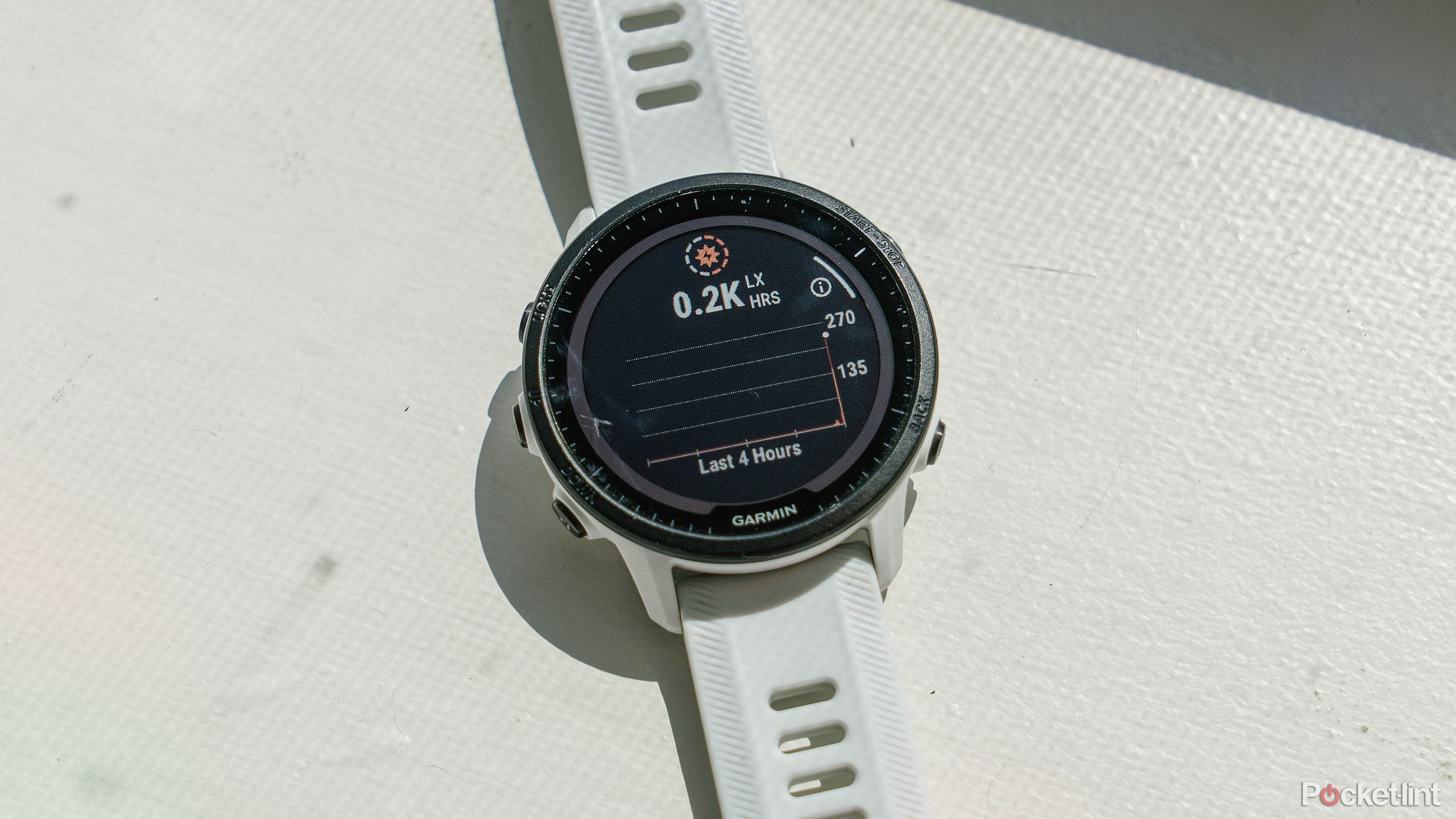 The Garmin Forerunner 955 Solar sits on a white windowsill with the solar intensity menu on the display. 