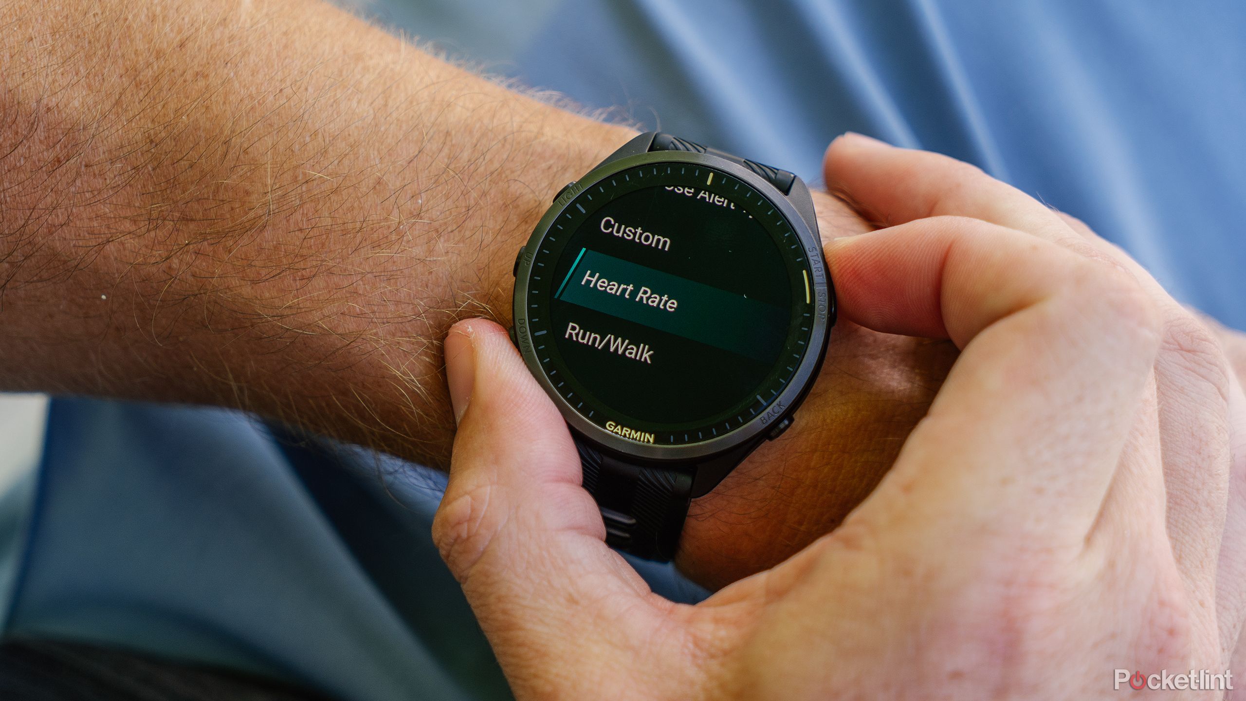 A hand presses buttons on the Garmin Forerunner 965 while it's on a wrist. 