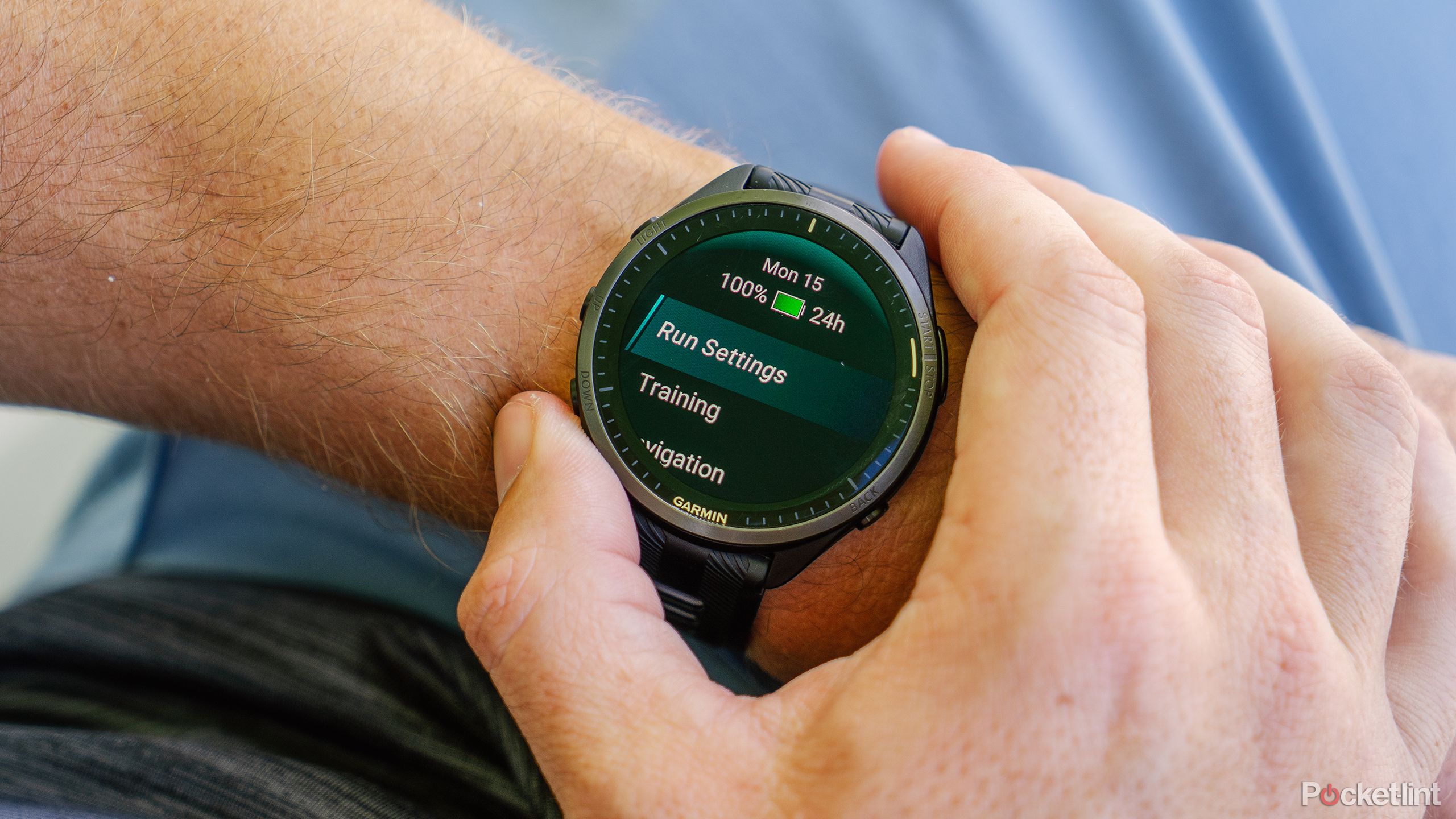 A hand presses buttons on the Garmin Forerunner 965 while it's on a wrist. 