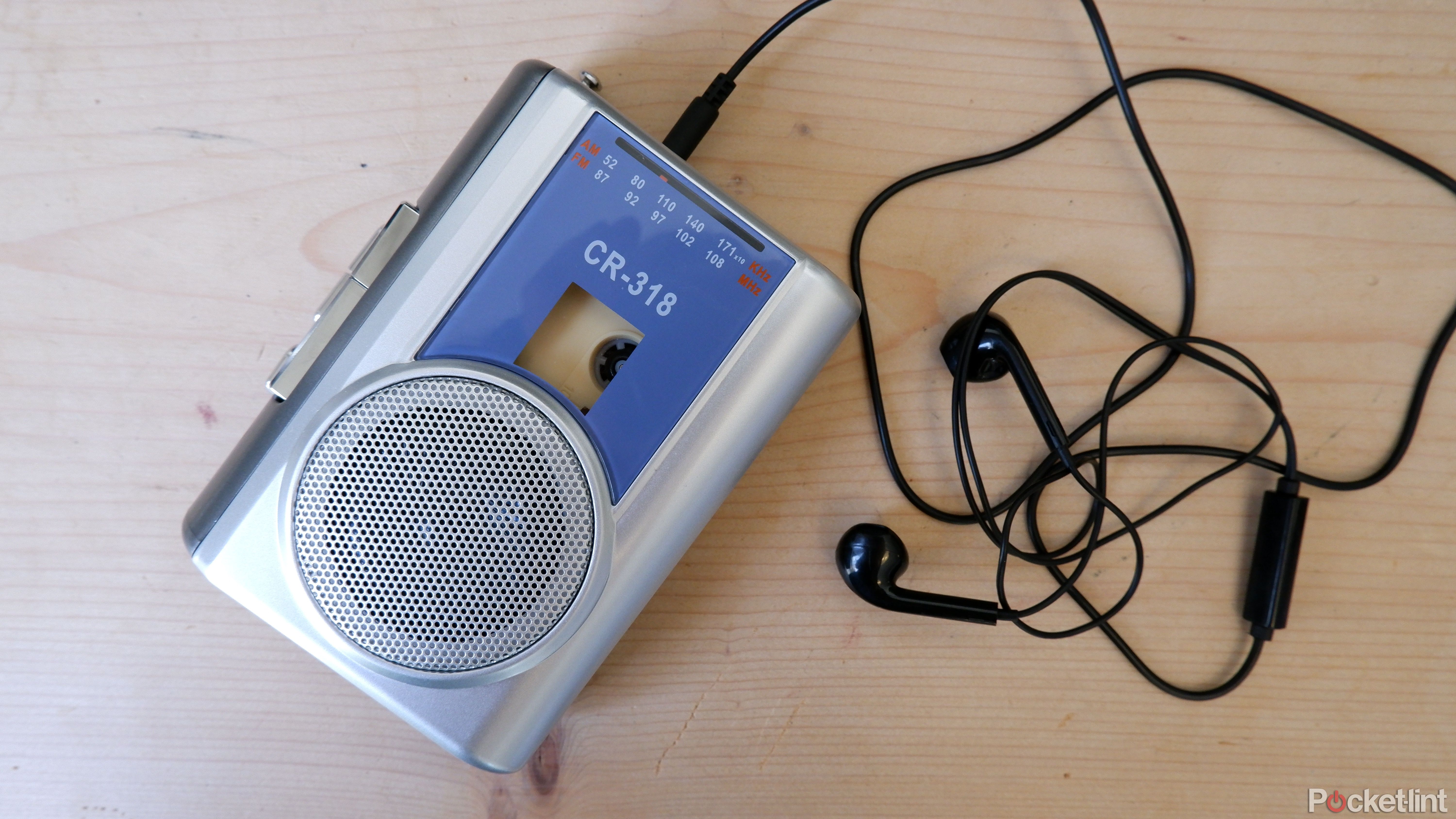 The Gracioso cassette player on a wooden surface with earbuds plugged in