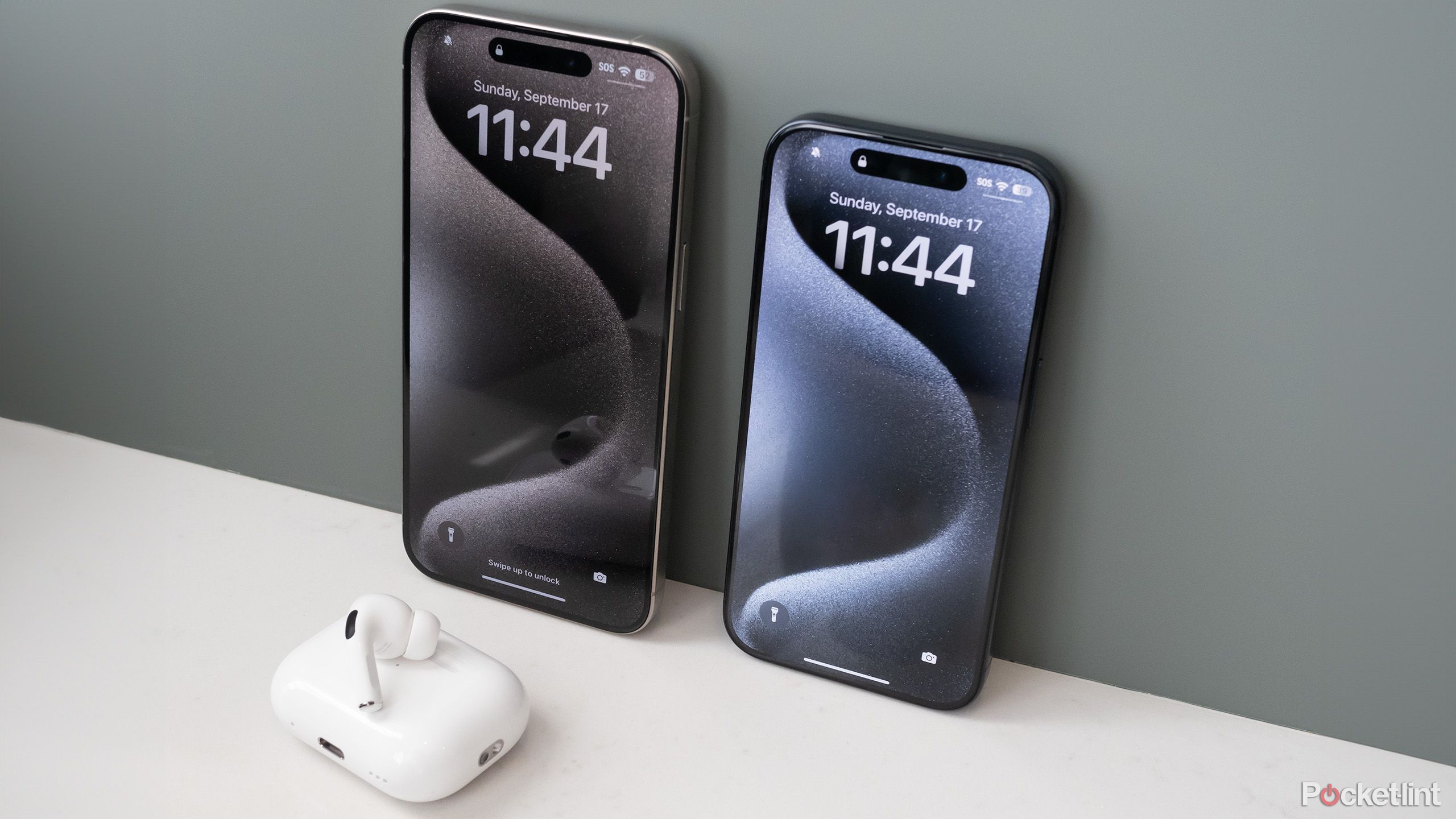 Two iPhone 15s next to AirPods.