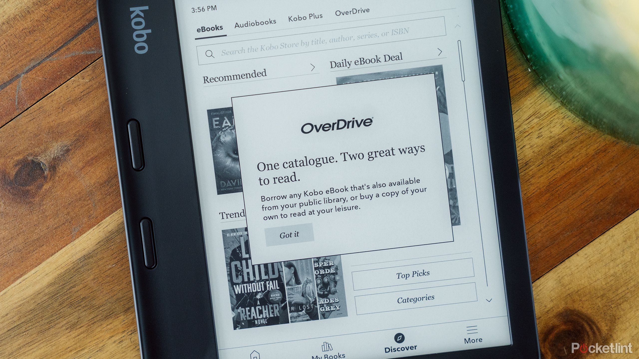 The Kobo Libra 2 on a wood table displays the OneDrive feature for renting books.