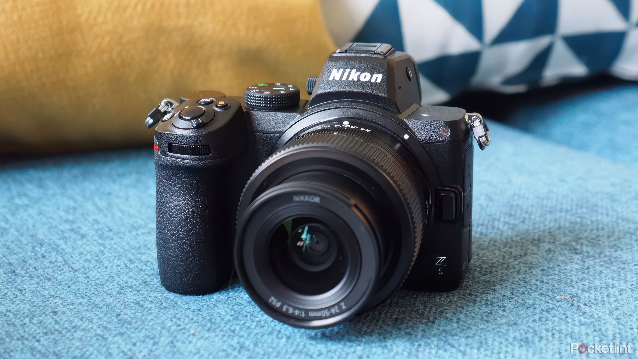 The Nikon Z5 mirrorless camera on a blue couch with pillows behind it. 