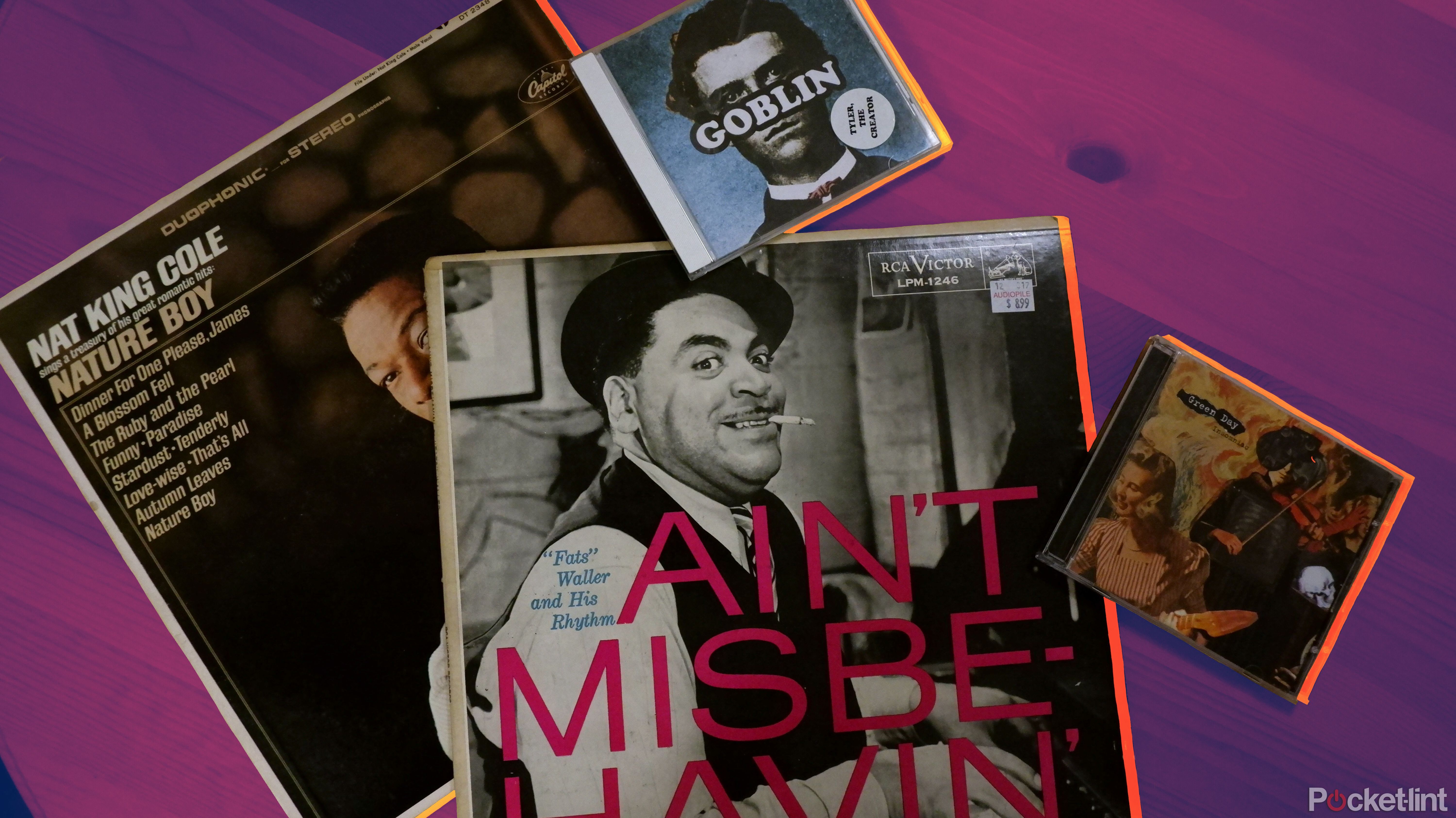 A Nat King Cole and Fats Waller record alongside Tyler, The Creator and Green Day albums, on a wooden table.