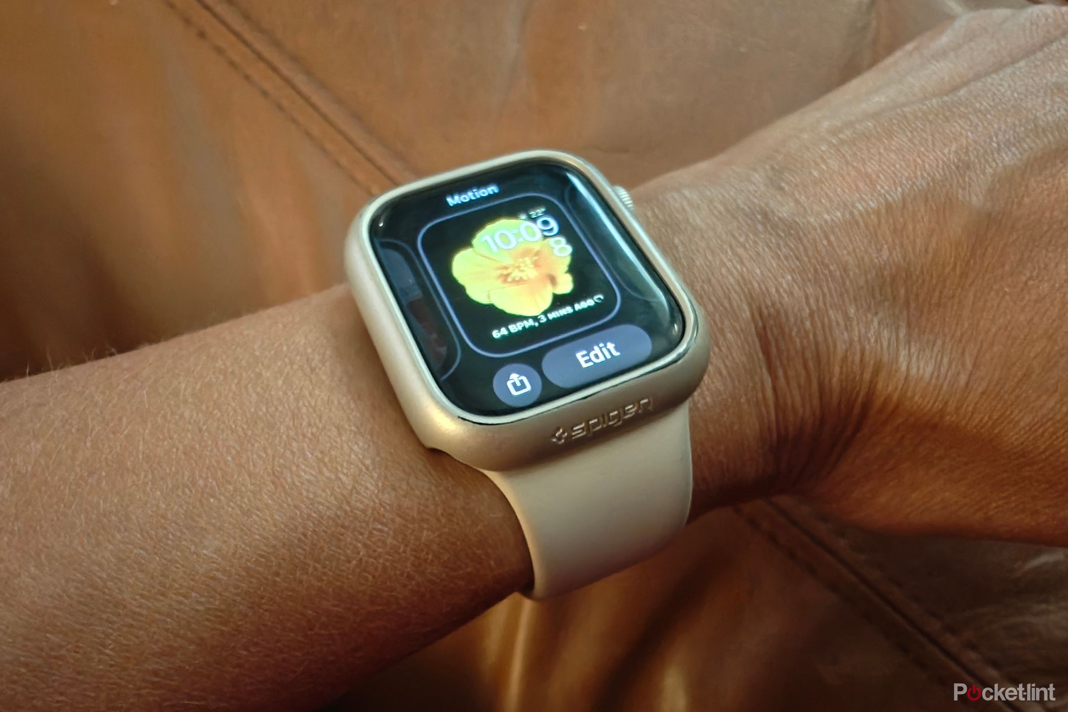 an Apple Watch with the edit option open to swipe among various face options, showing a Motion one with a yellow flower.