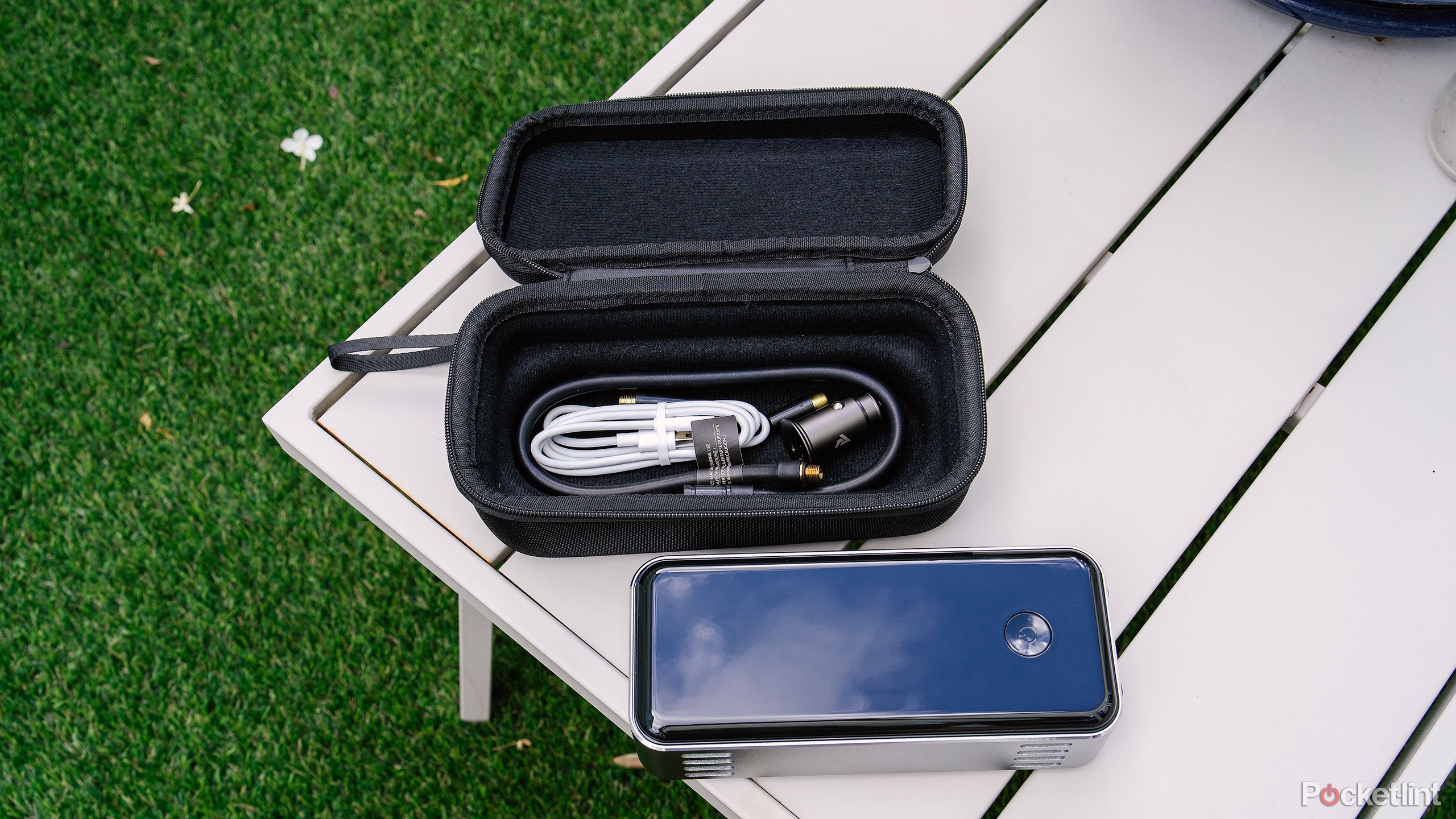 The Denvix Portable Air Compressor sits on a metal outdoor coffee table with its case and accessories