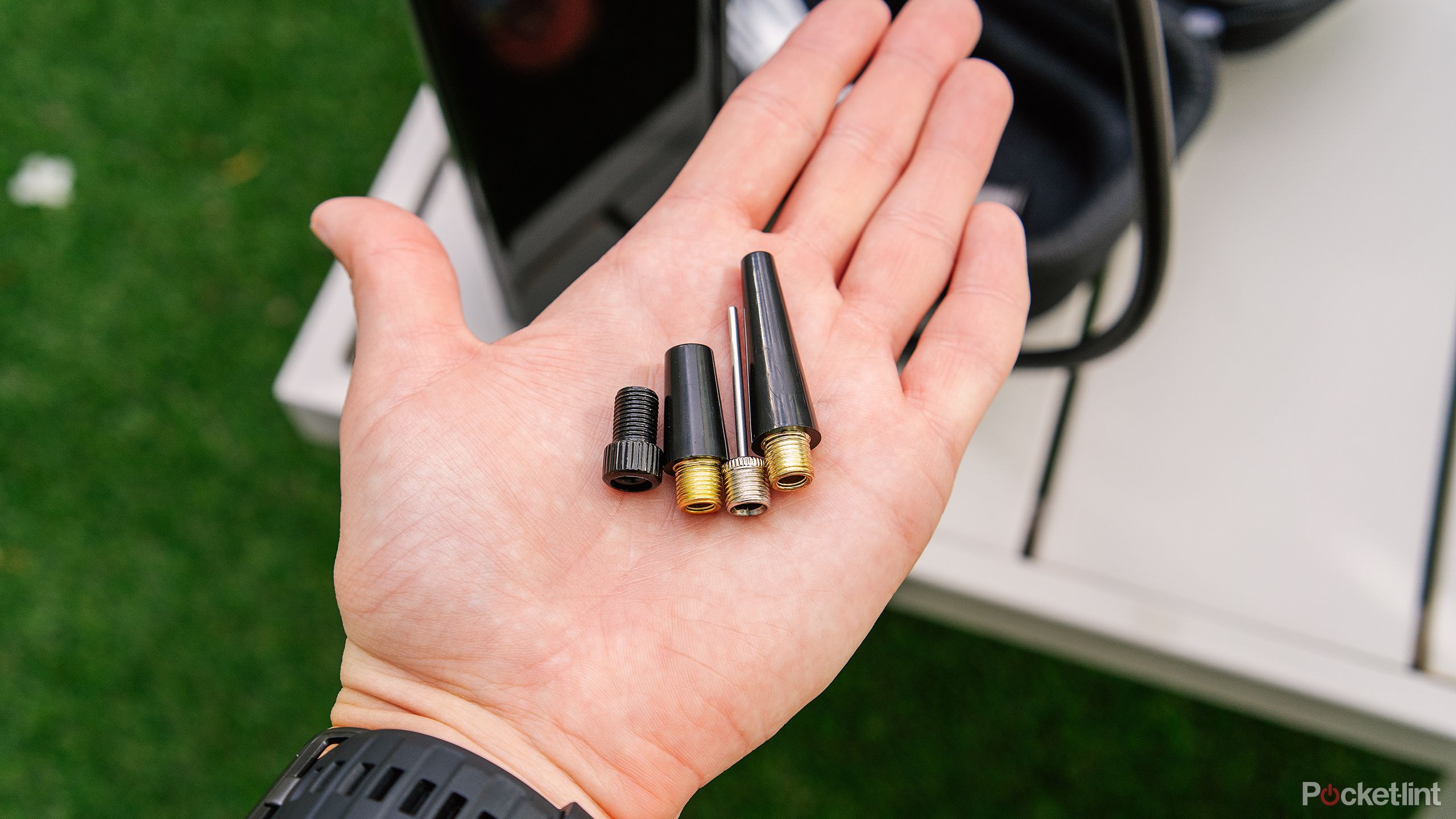 A hand holds the adaptors for the Denvix Portable Air Compressor. 