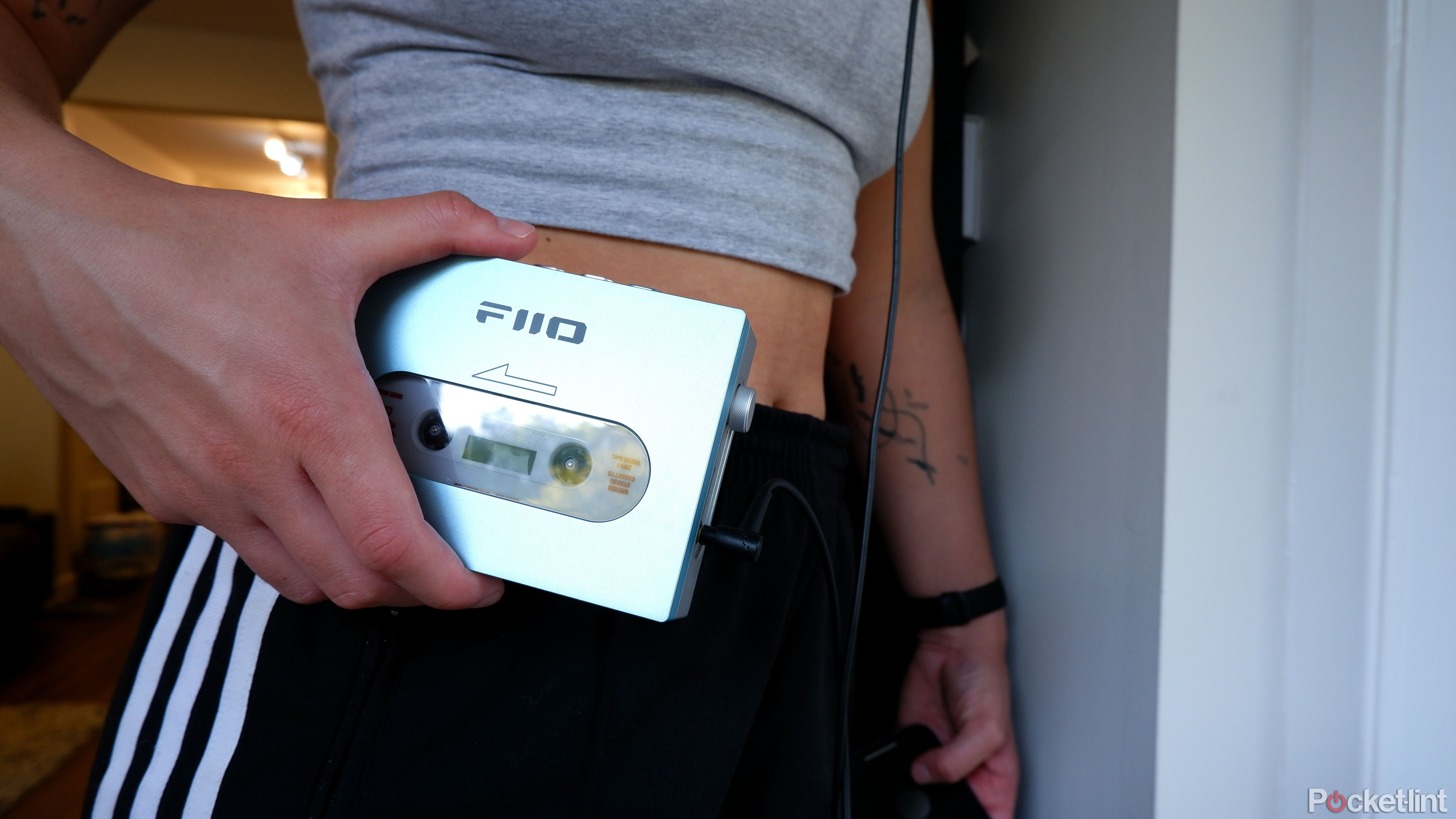 The Fiio CP13 being held in a hand next to a person's hip