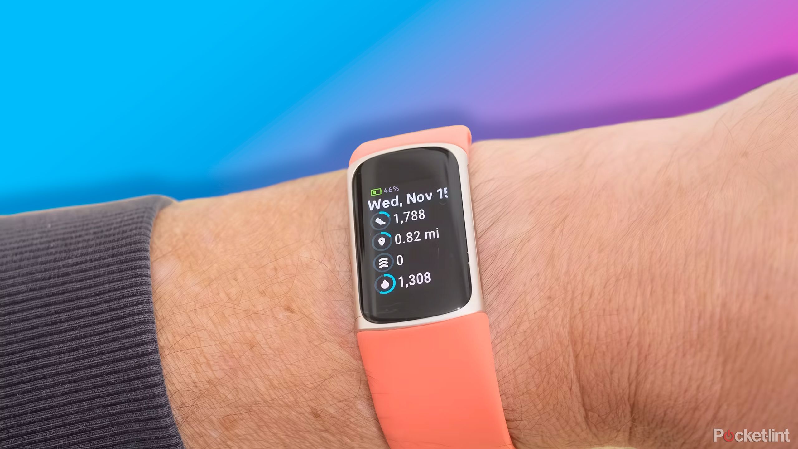 The Fitbit Charge 6 on a wrist in front of a purple to pink gradient. 