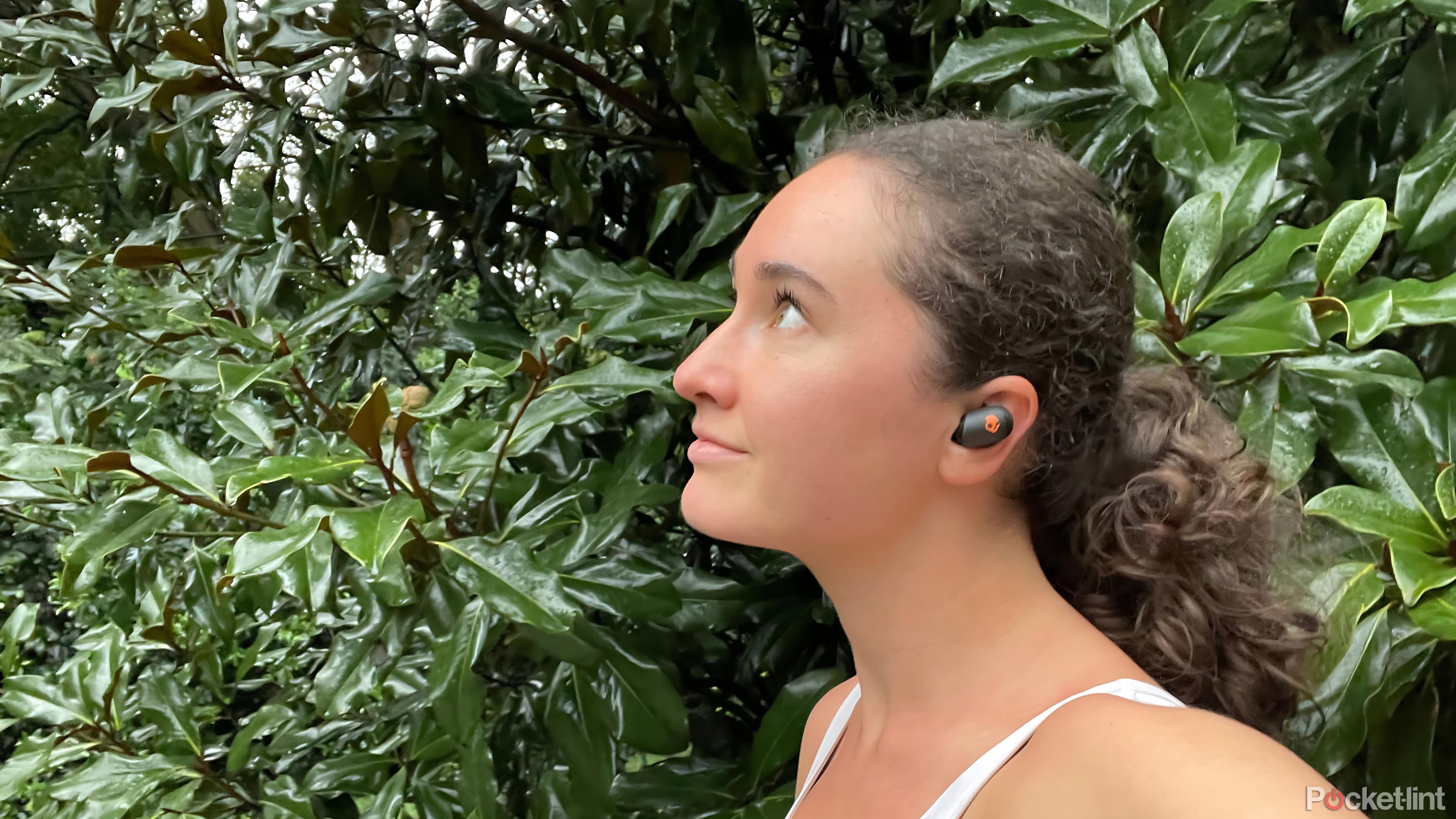 A woman wearing Skullcandy Sesh ANC Active earbuds in the rain. 