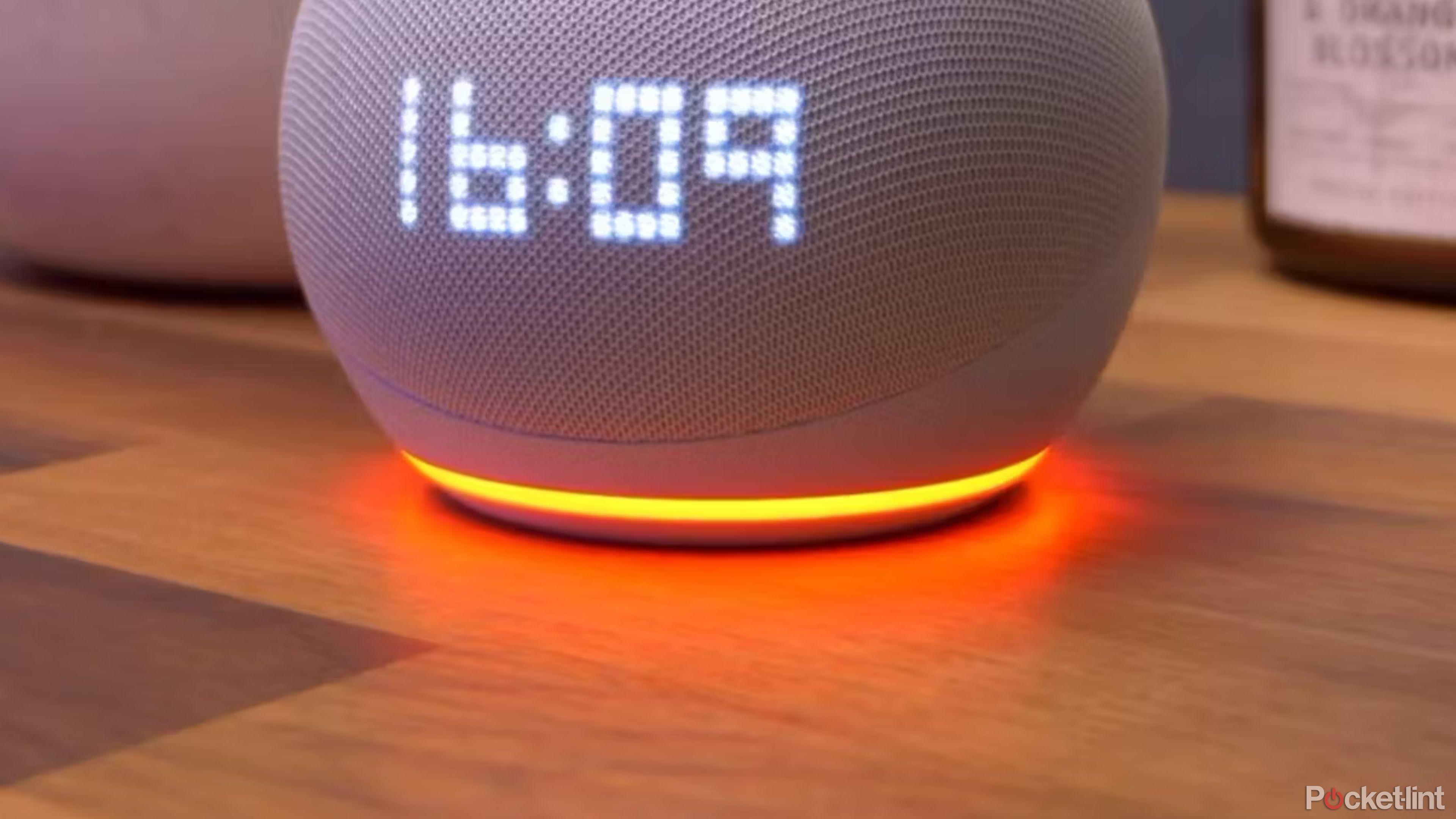 Un Echo Dot con un anillo naranja se encuentra sobre una superficie de madera.