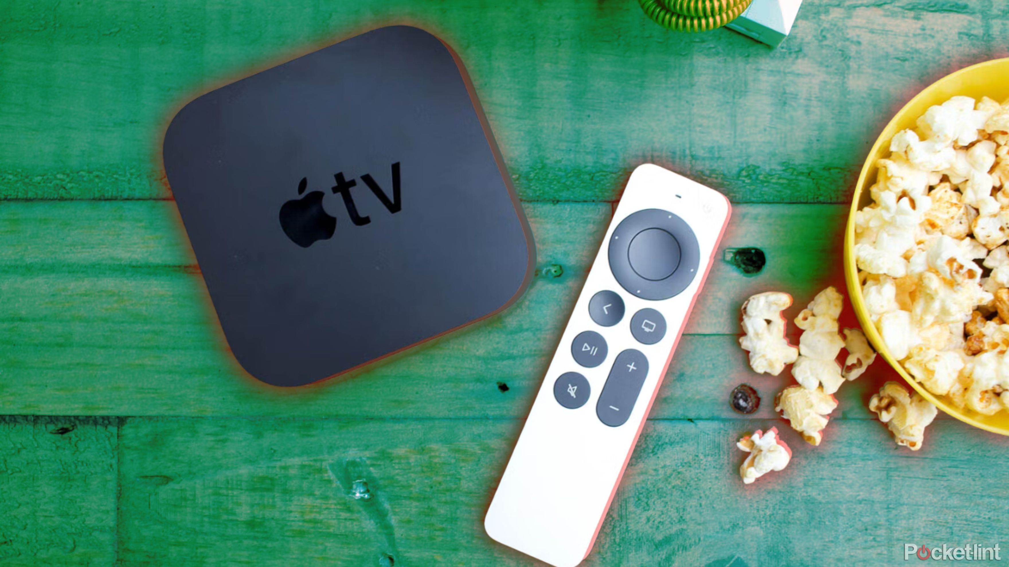 Apple TV e controle remoto em mesa de madeira com pipoca