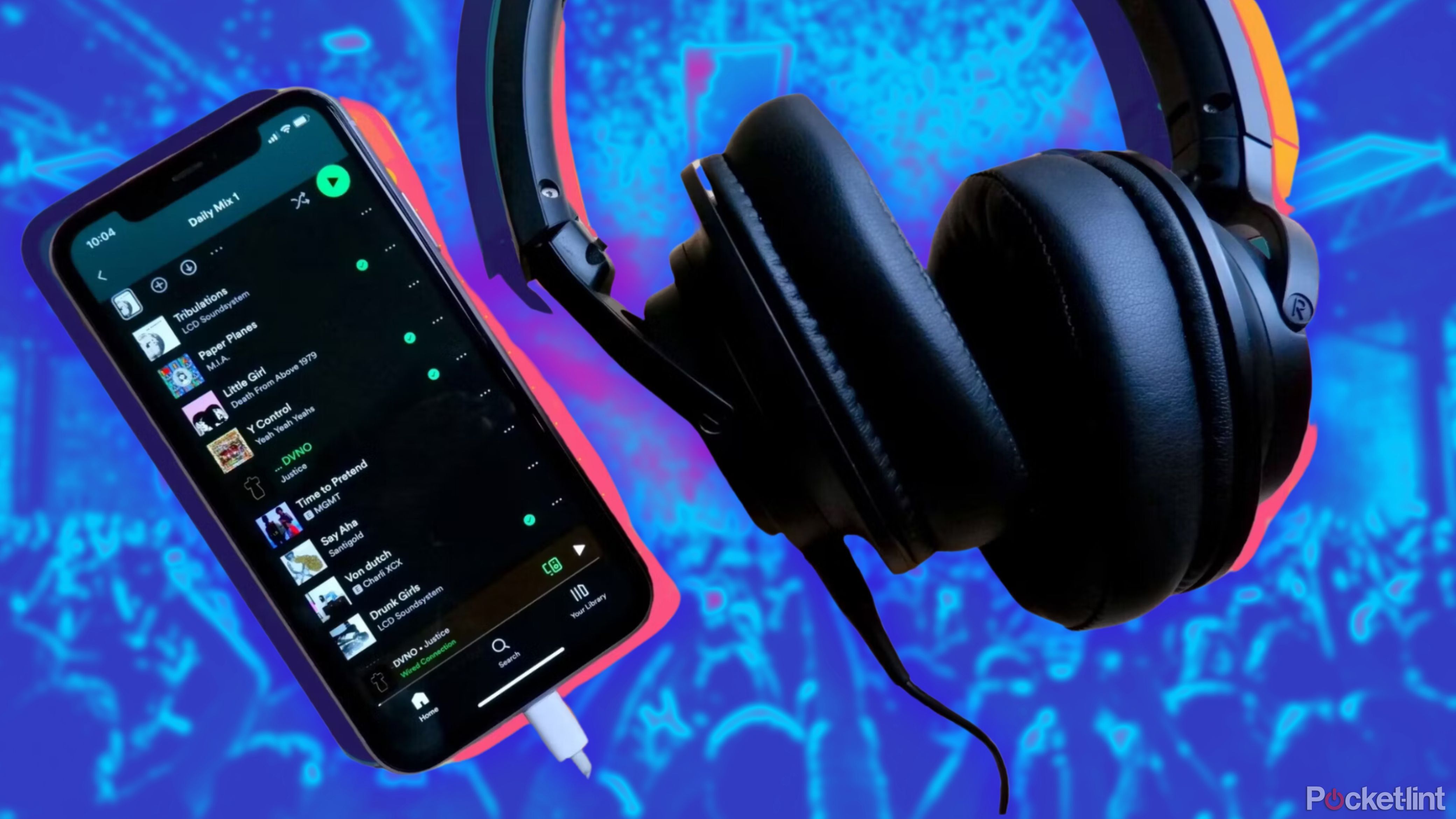 An iPhone with Spotify open with a pair of headphones plugged in against a concert scene