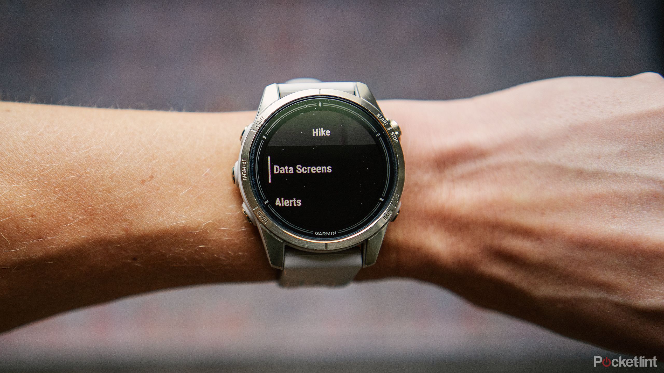 A wrist is held out over a blurred rug with the Garmin epix Pro Gen 2 on it displaying the Dara Screens menu. 