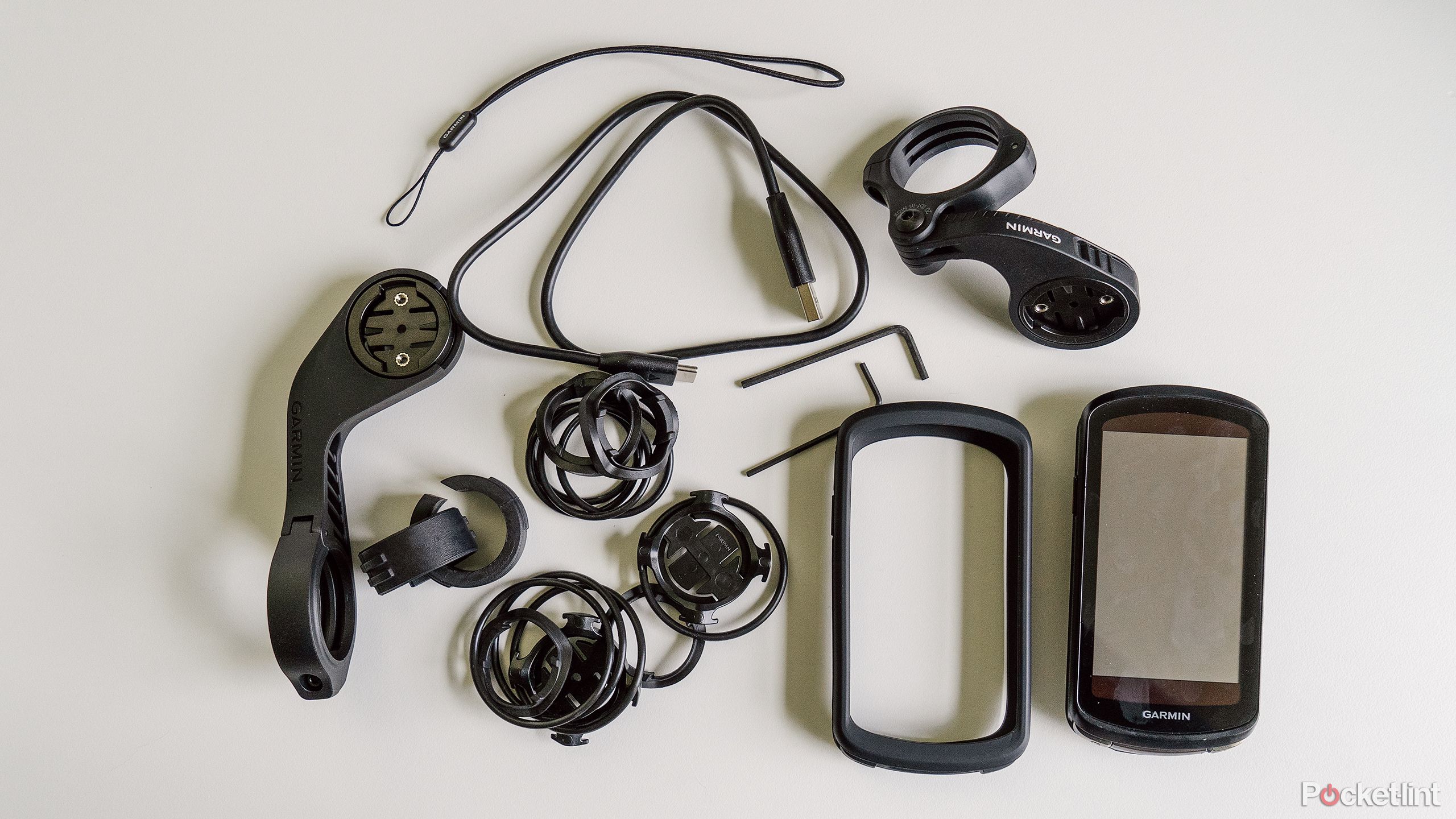 The Garmin Edge 1040 Solar and all of its accessories sit on a white desk. 