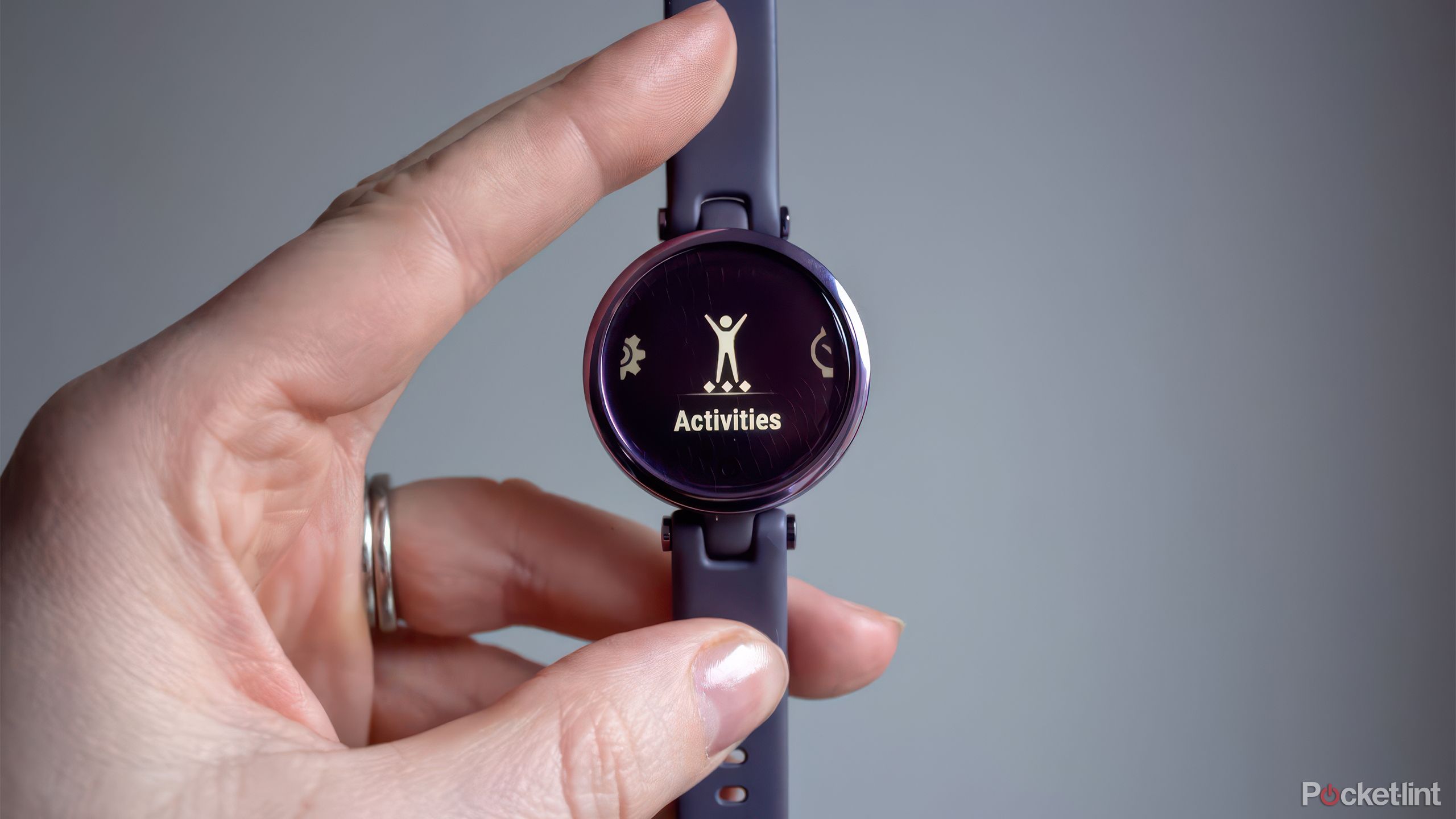 A hand holds the purple Garmin Lily against a gray background. 