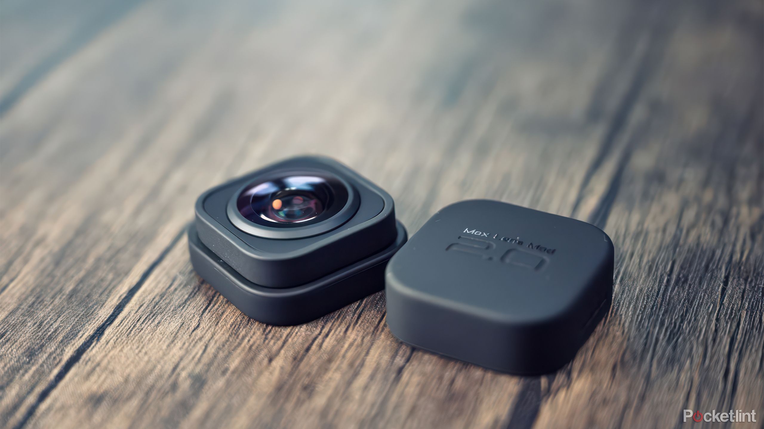 The GoPro Max Lens Mod sits on a wooden table with its cover still on. 