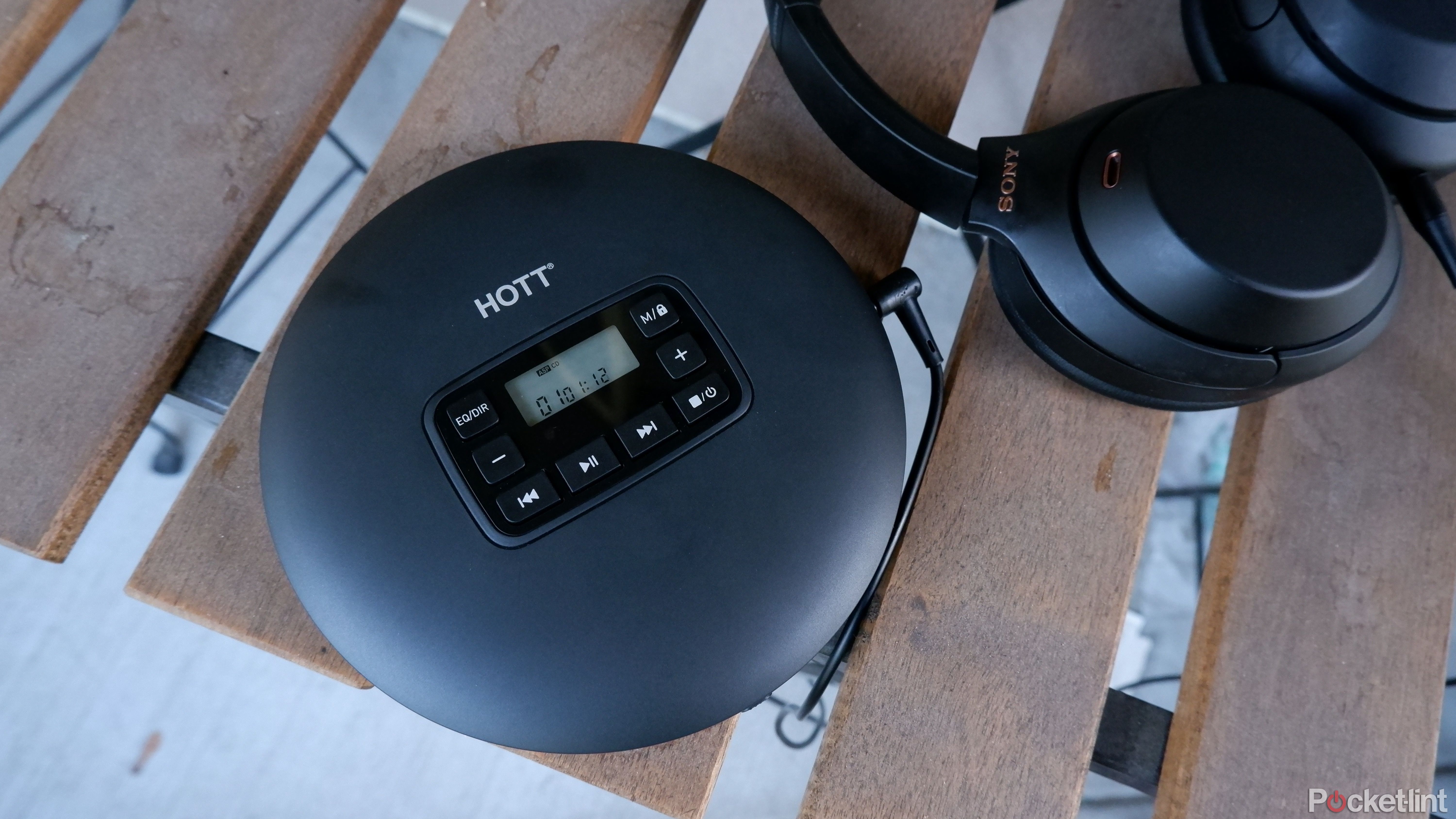 Hott CD204 on a patio table alongside over-ear headphones