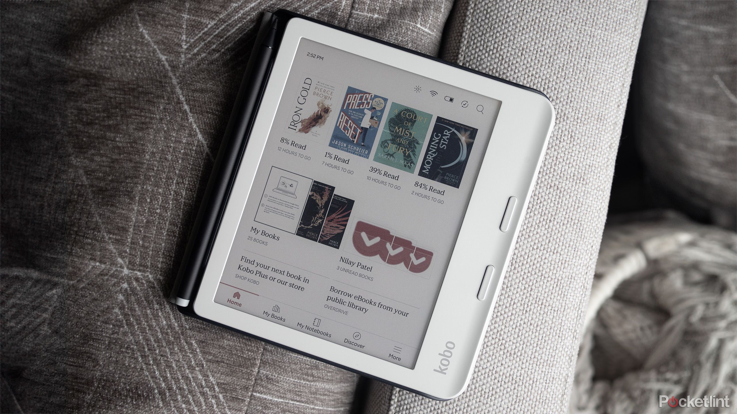 The Kobo Libra Colour sits on a gray couch. 