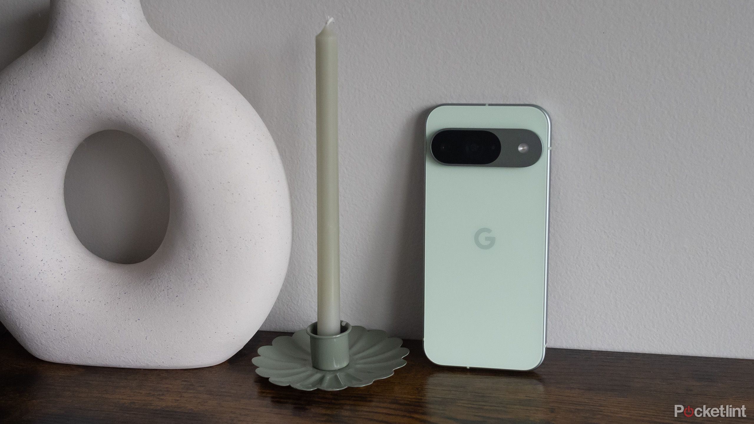 The Pixel 9 beside a green candle