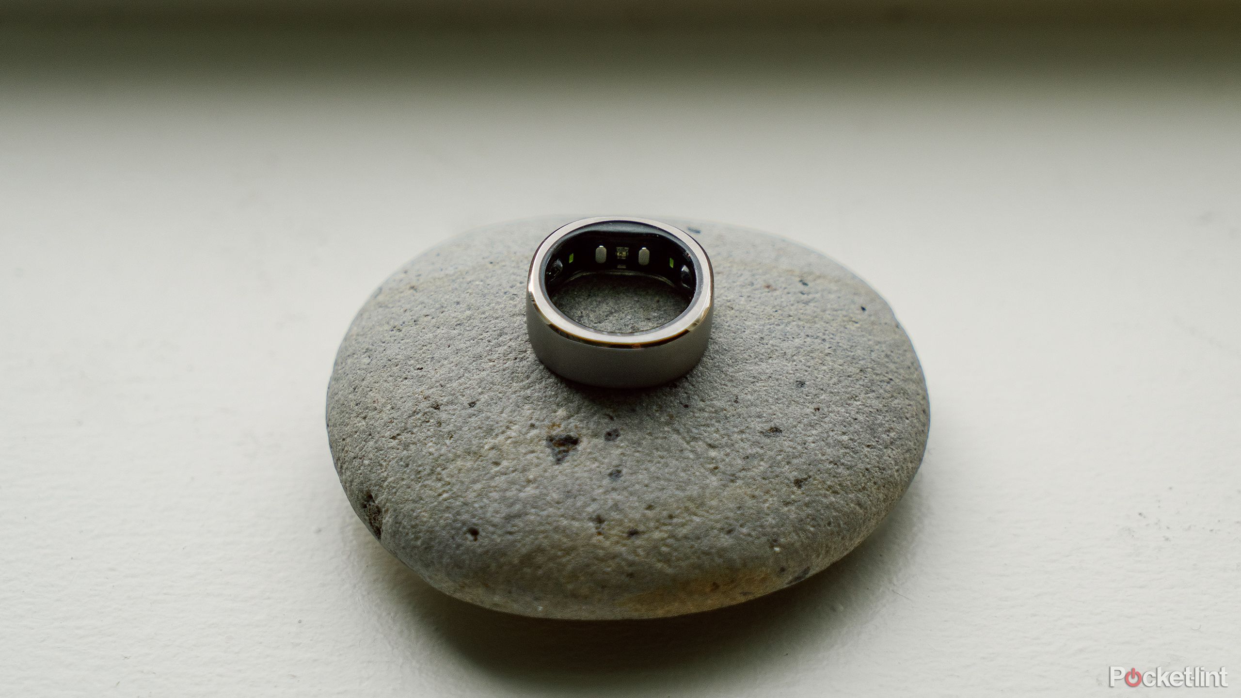 The RingConn Smart Ring sits on a gray rock on a white windowsill. 