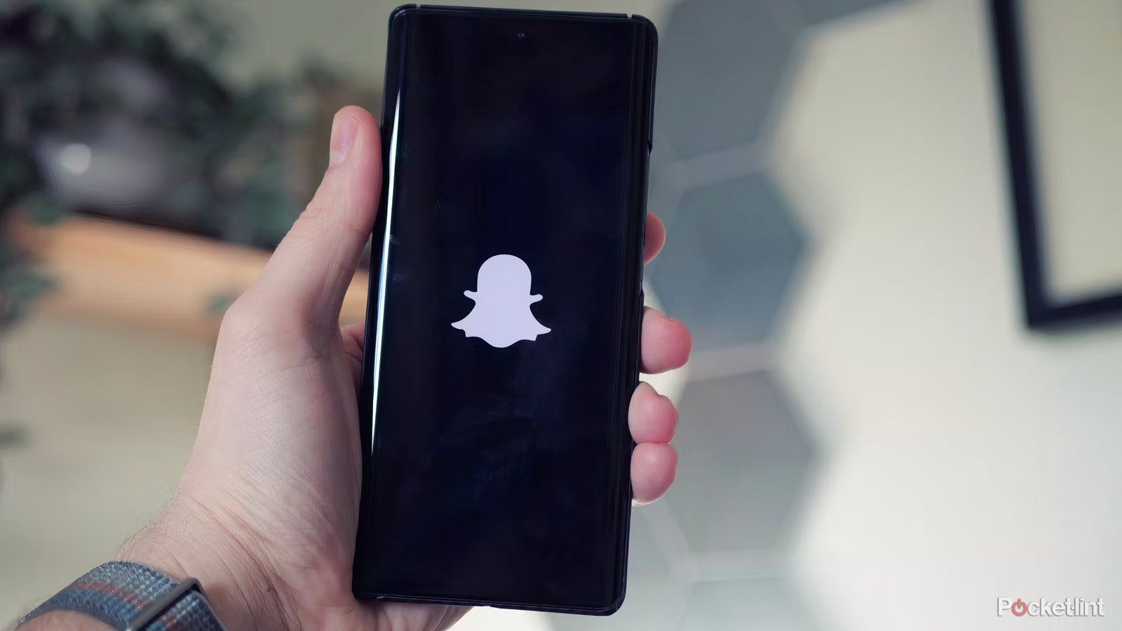 A photo of an hand holding a smartphone with the Snapchat logo