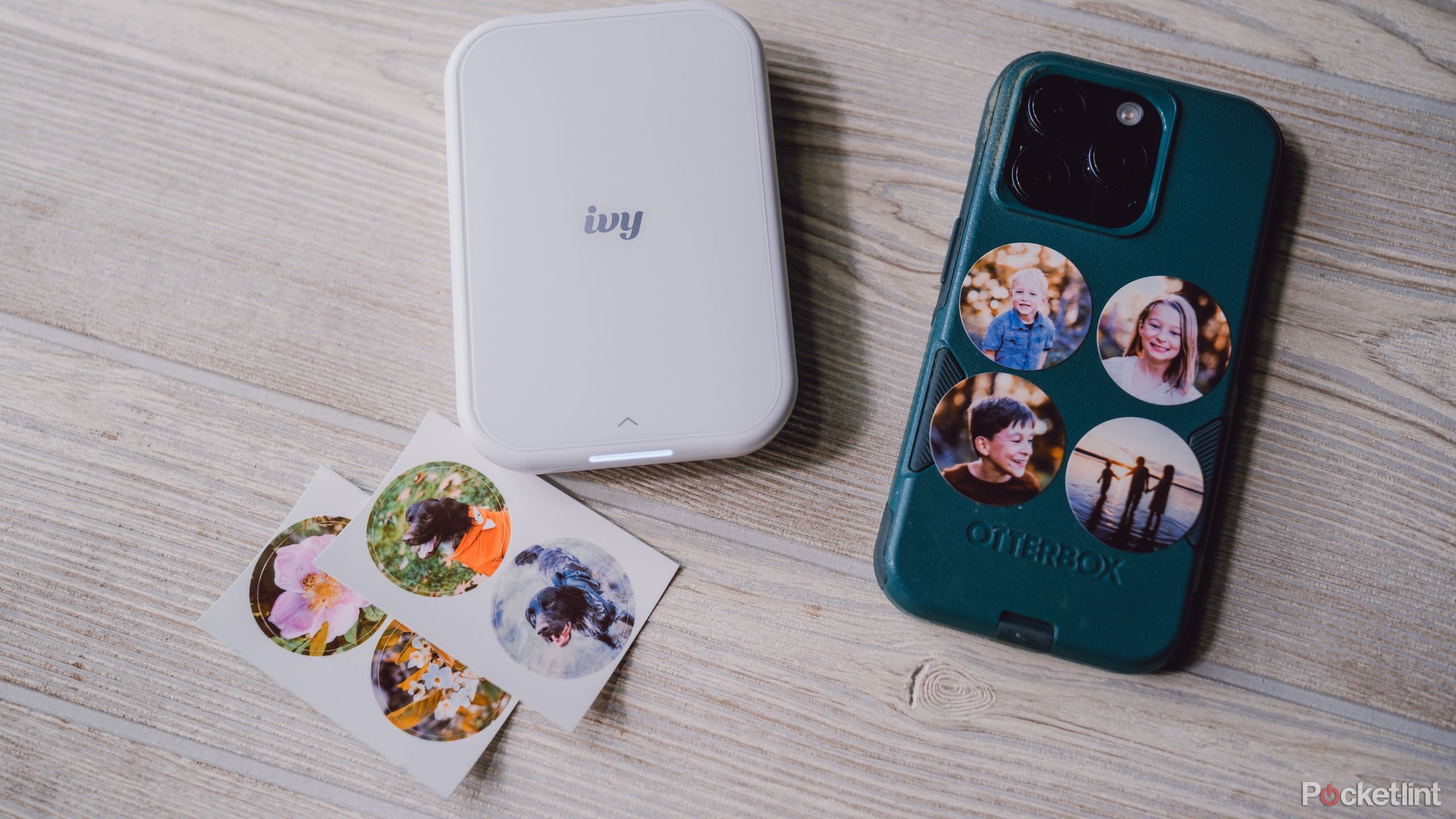 The Canon Ivy 2 sits with an iPhone covered in stickers