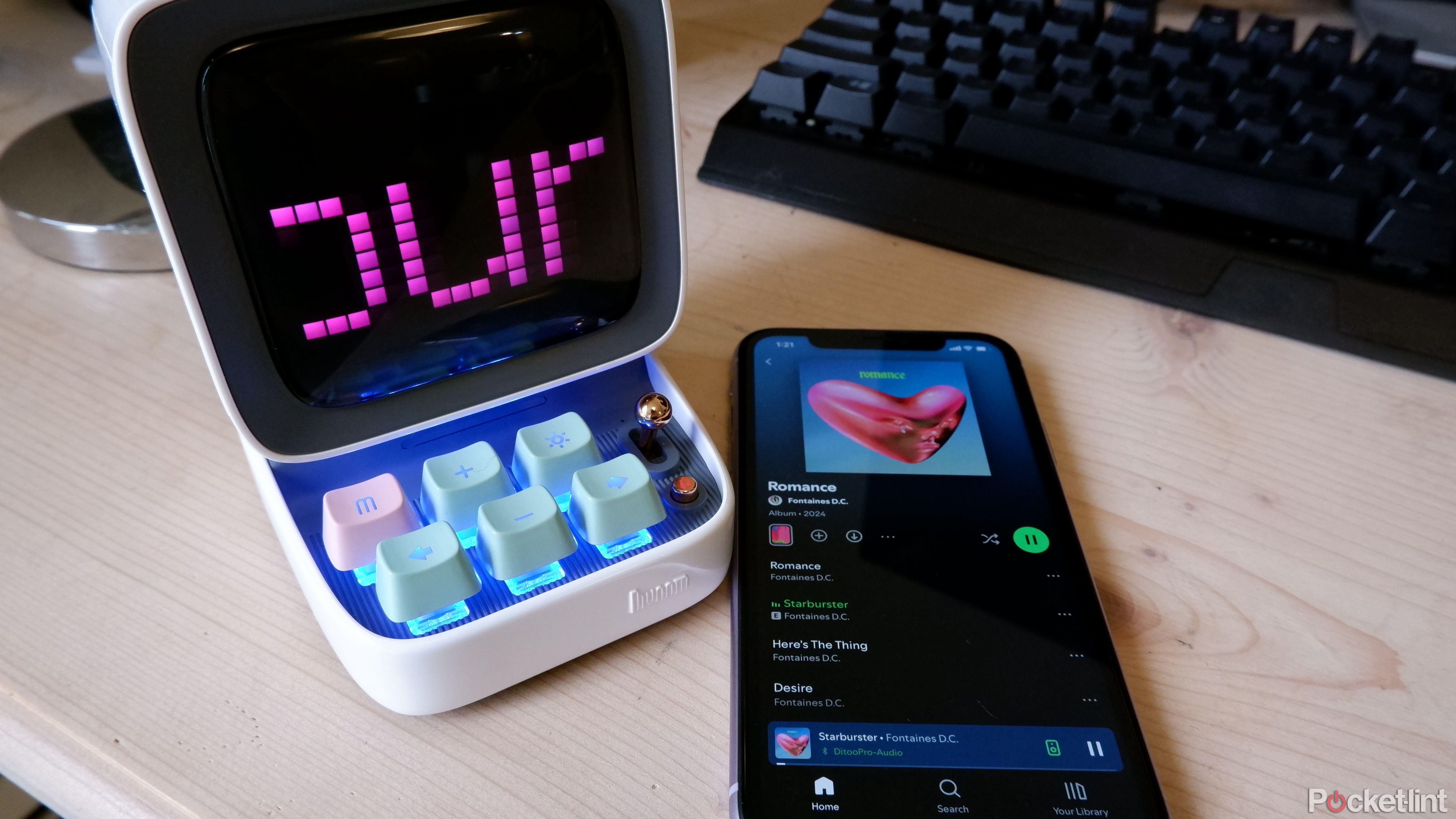 Le Divoom Ditoo et un iPhone sur un bureau en bois, avec Spotify ouvert sur l'iPhone.