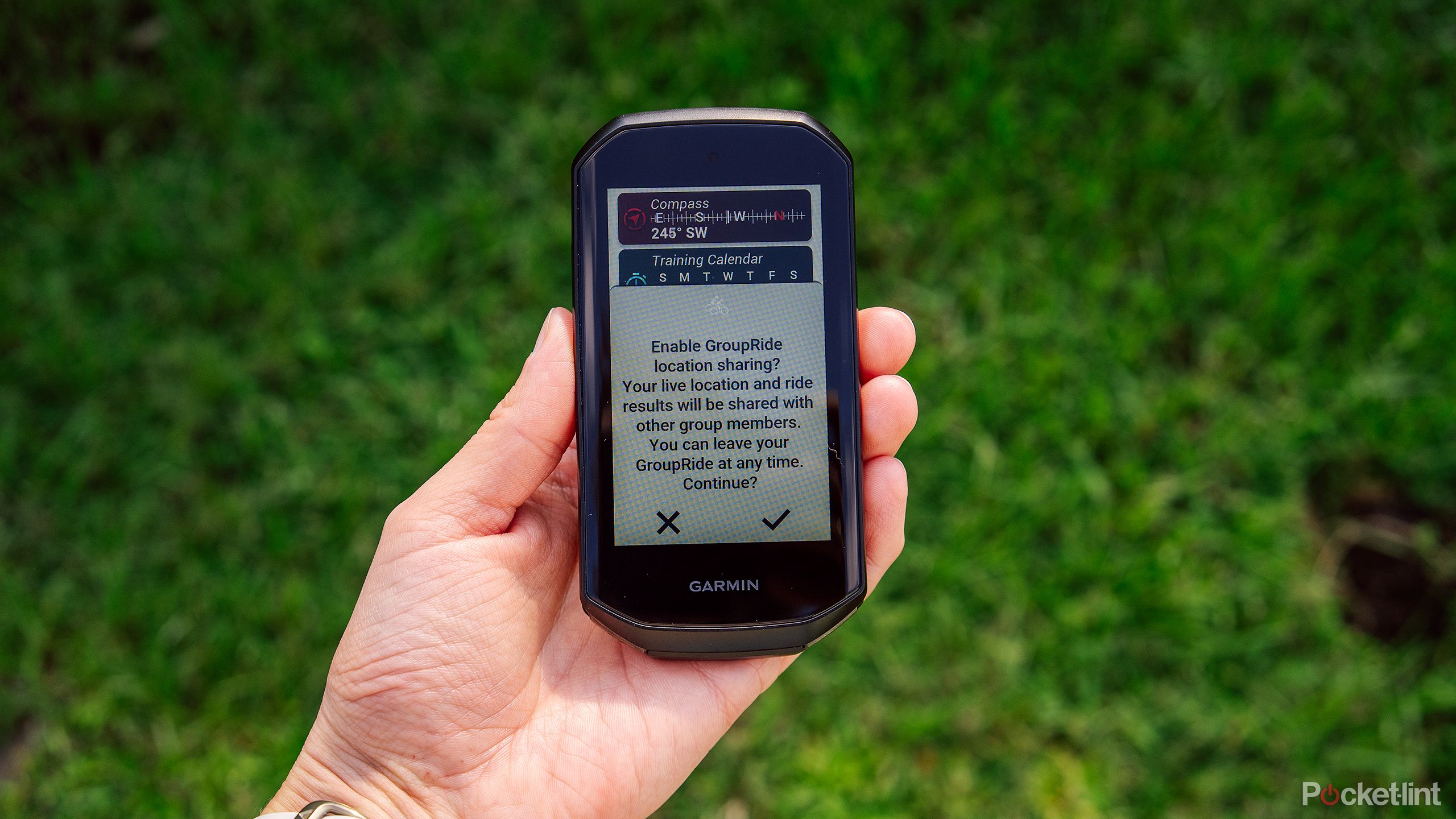 A hand holds the Garmin Edge 1050 with the GroupRide feature on the display. 