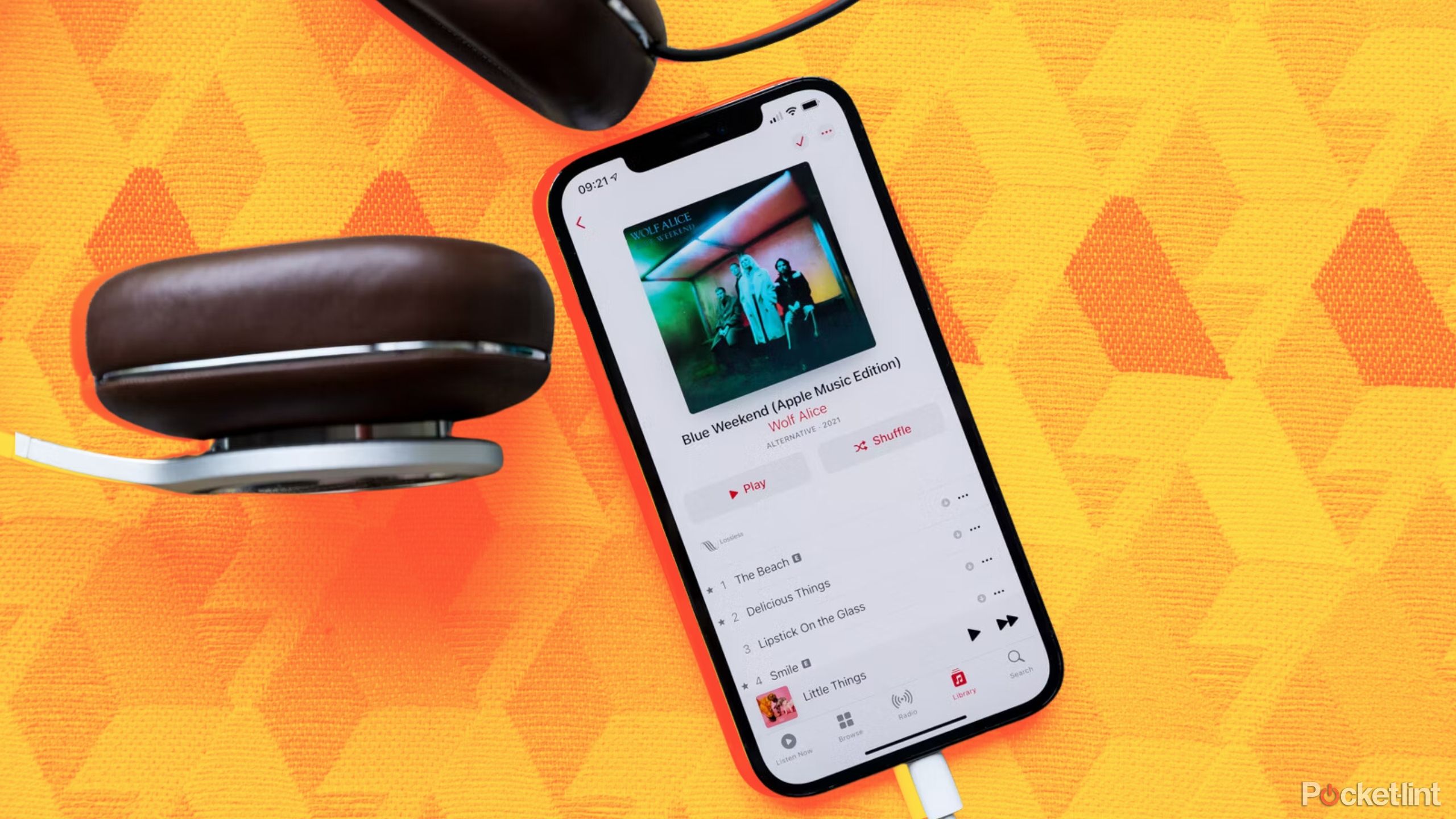 iPhone with wired headphones playing Apple Music on a colored background