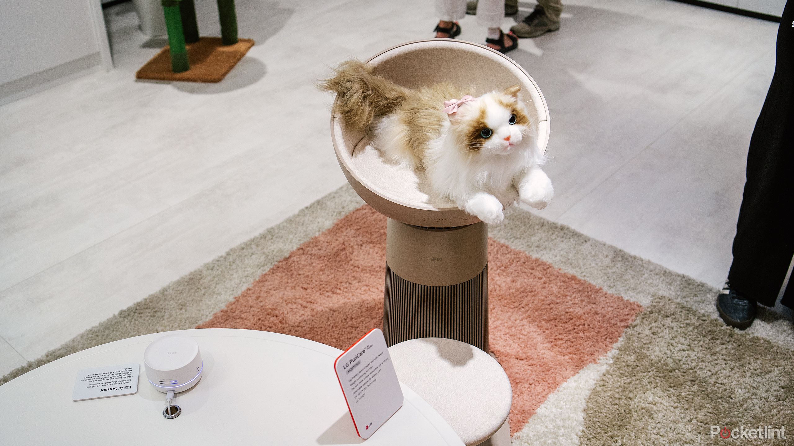 A stuffed cat is placed on an air purifier. 