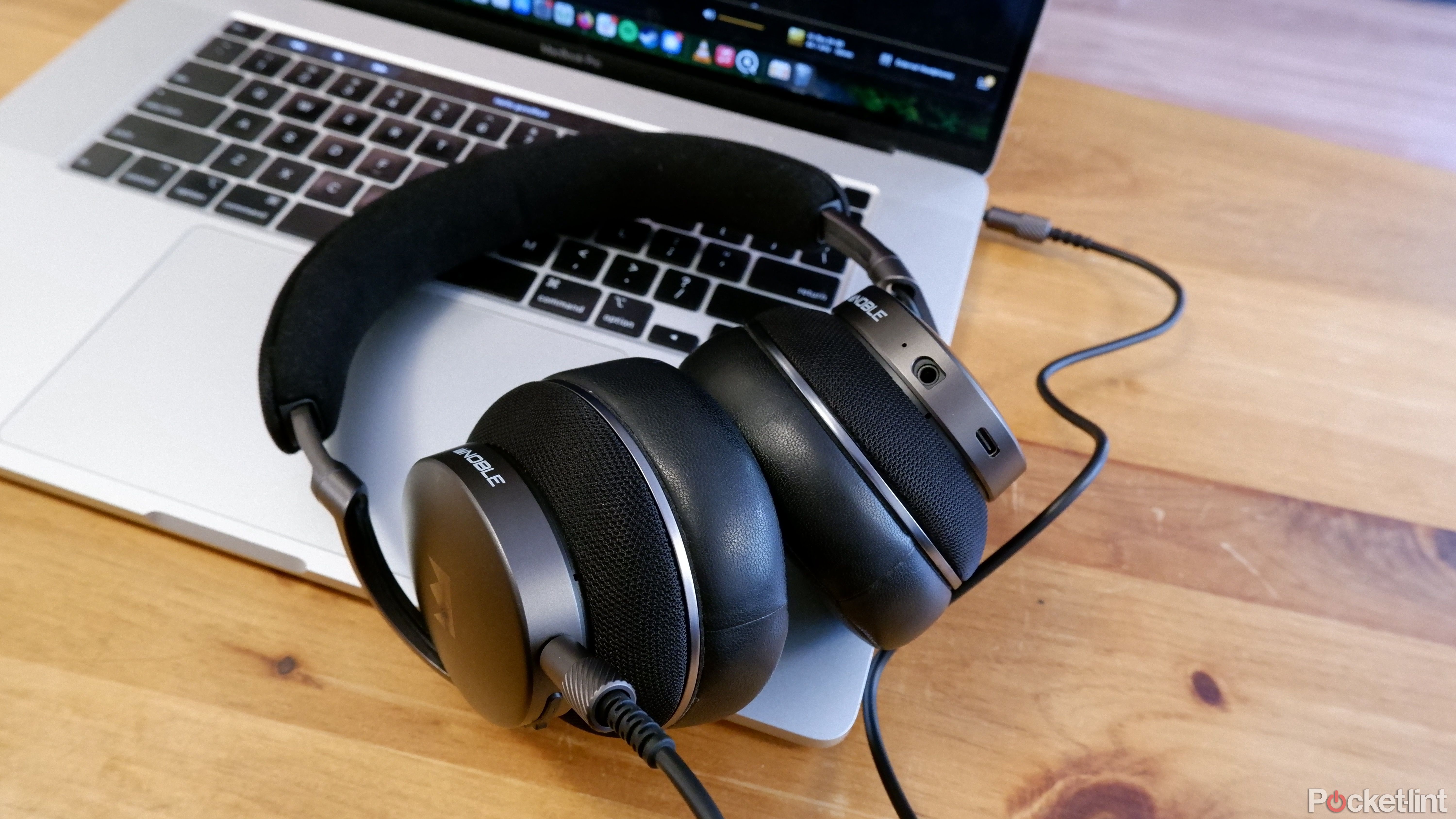 The Noble Fokus Apollo on top of a Macbook Pro, with the 3.5mm cable plugged in