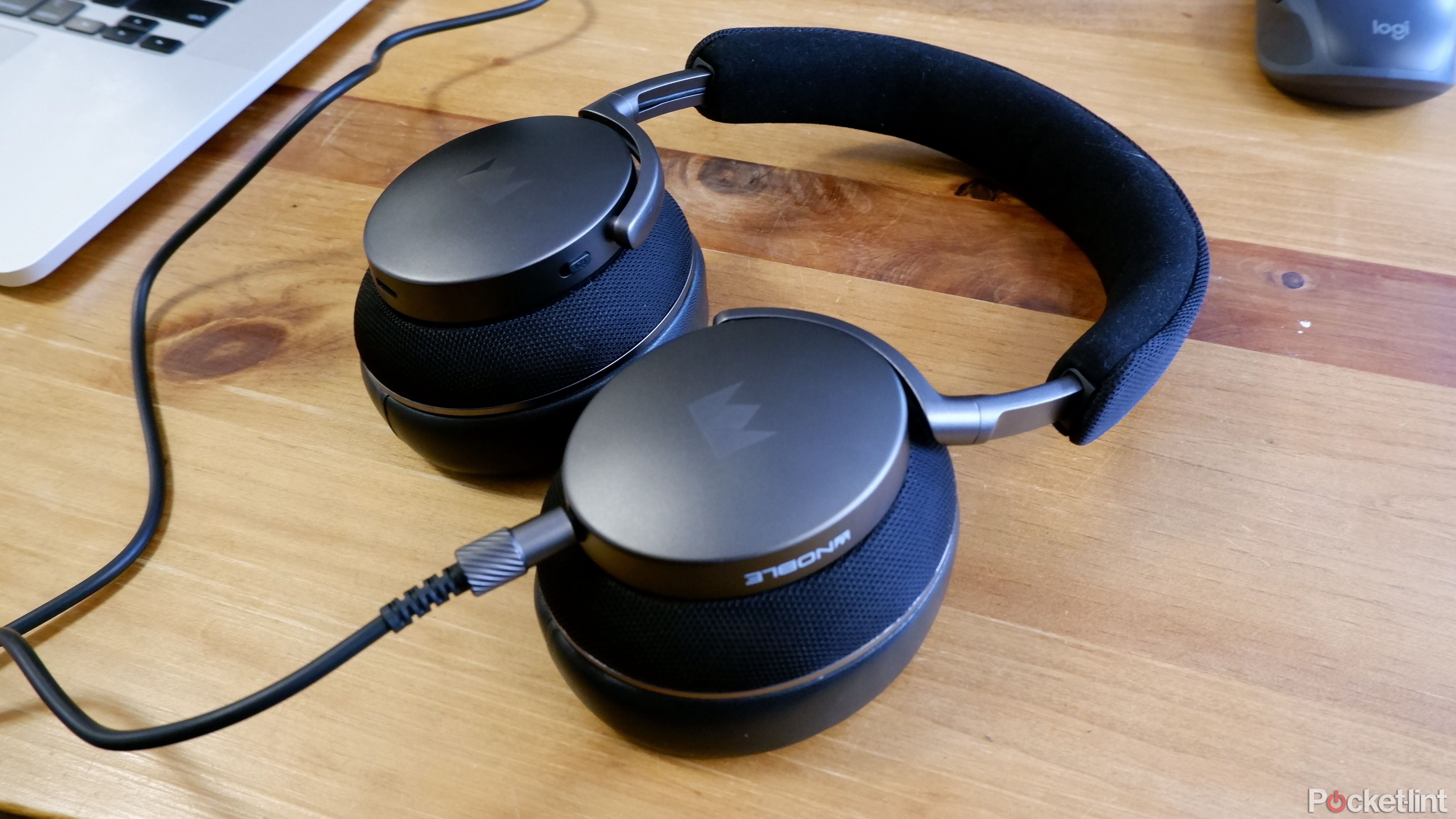 The Noble Fokus Apollo with the 3.5mm cable plugged into a laptop, on a wooden coffee table