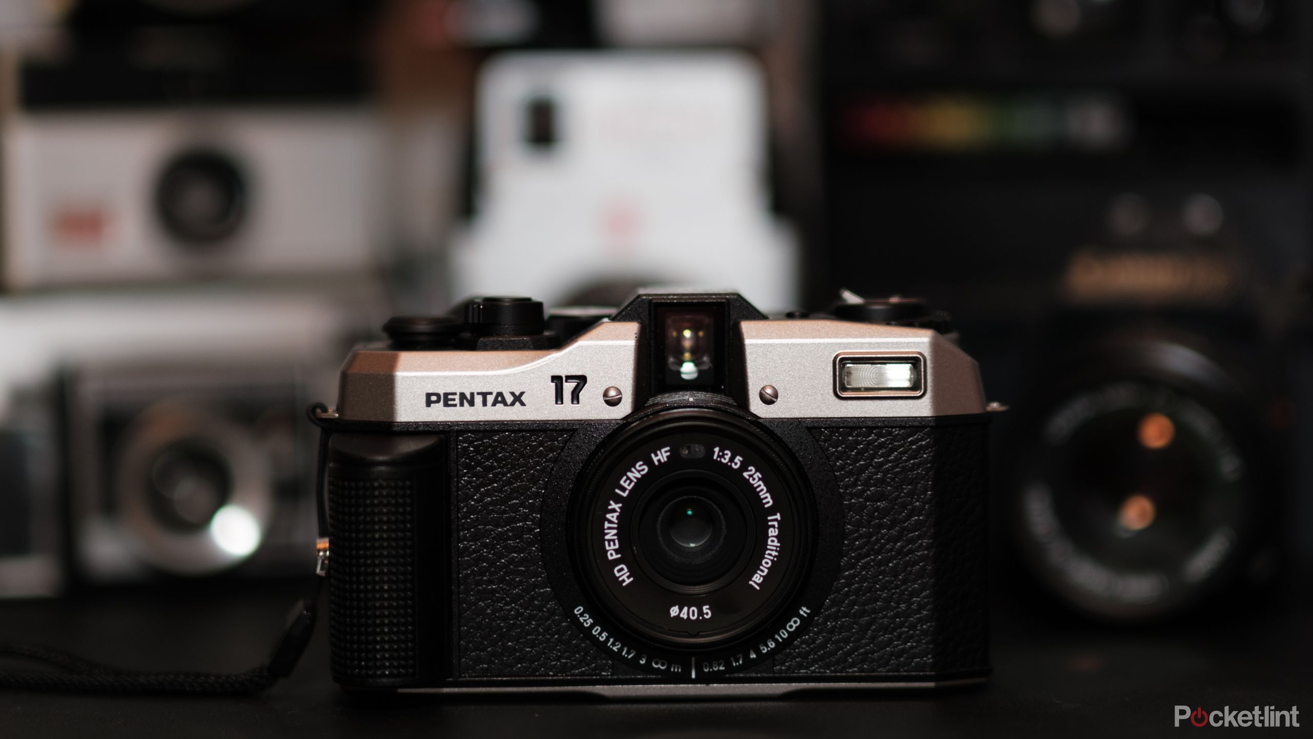 A photograph of the Pentax 17 film camera with other film cameras in the background