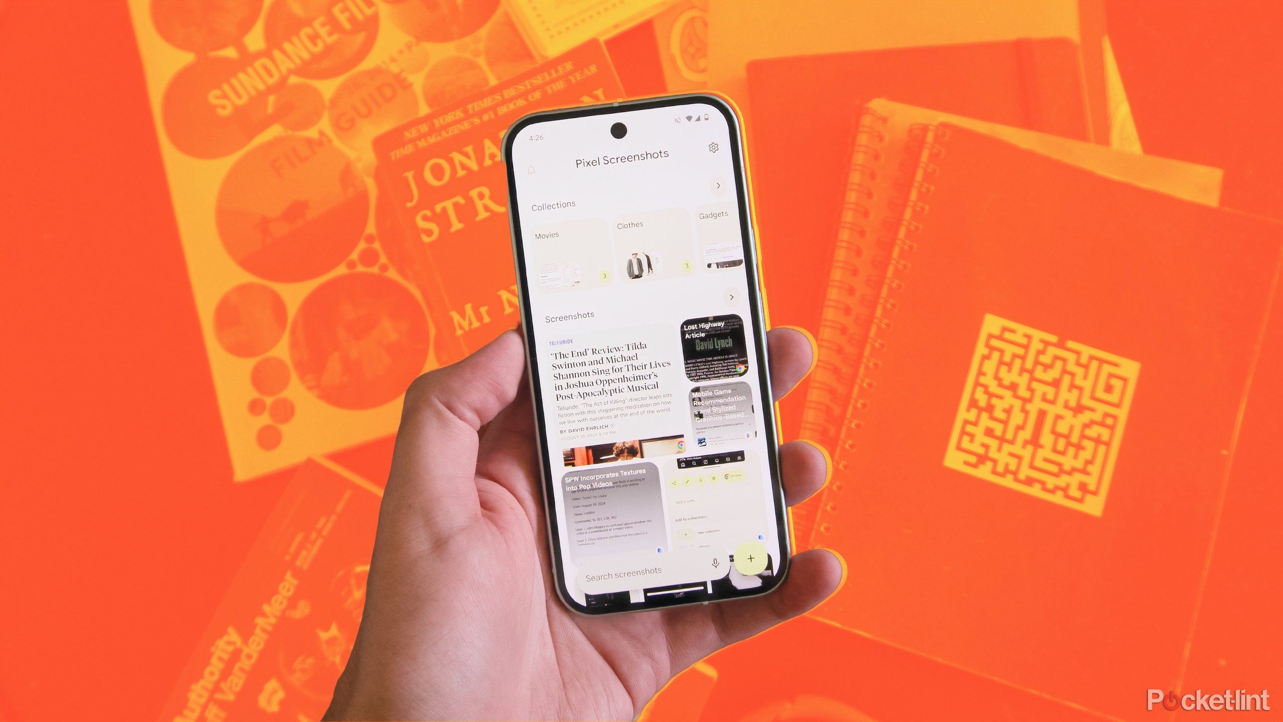 Holding the Pixel Screenshots app over a collection of books and notebooks.