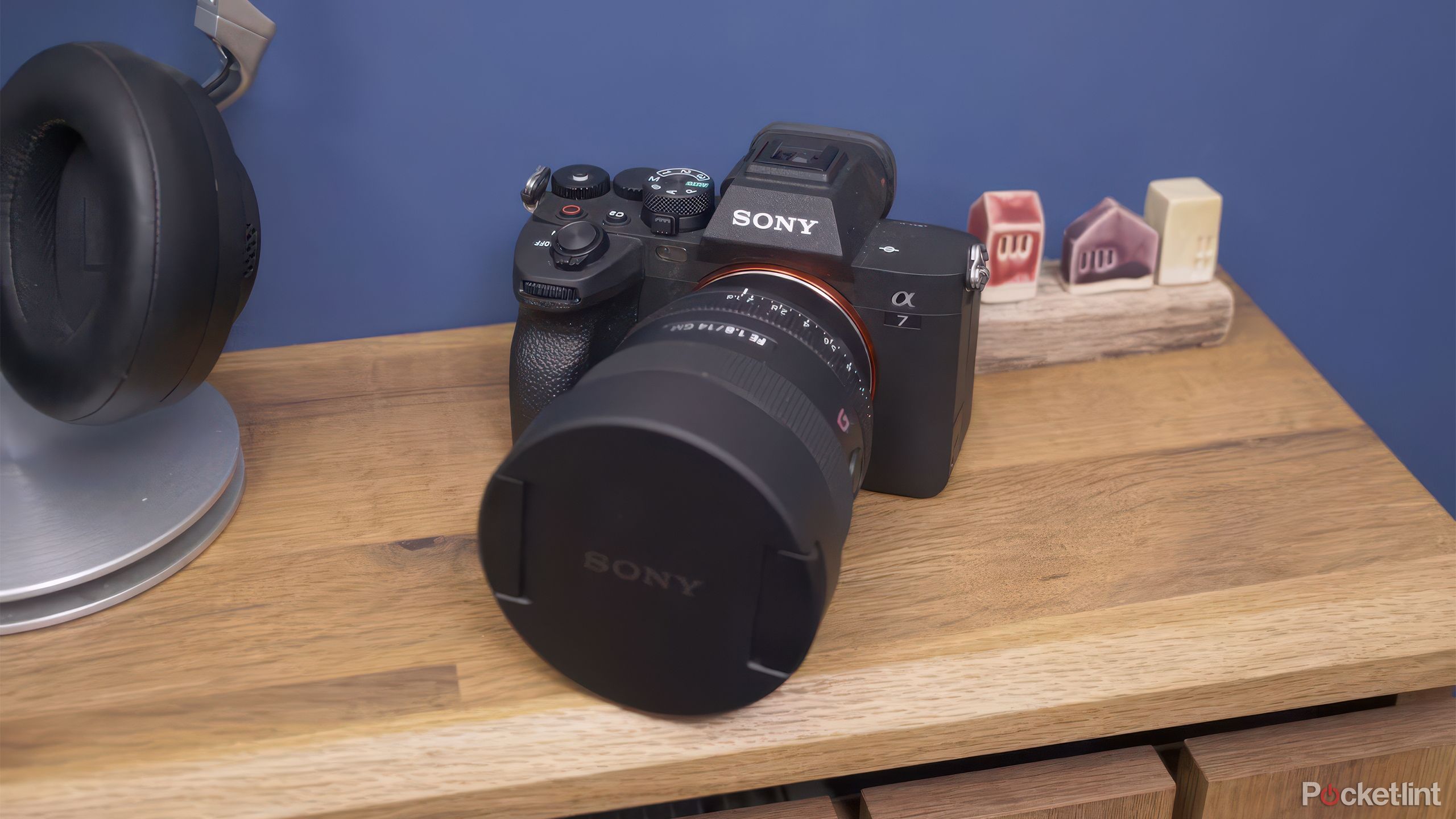 The Sony A7 IV sits on a table in front of a blue wall. 