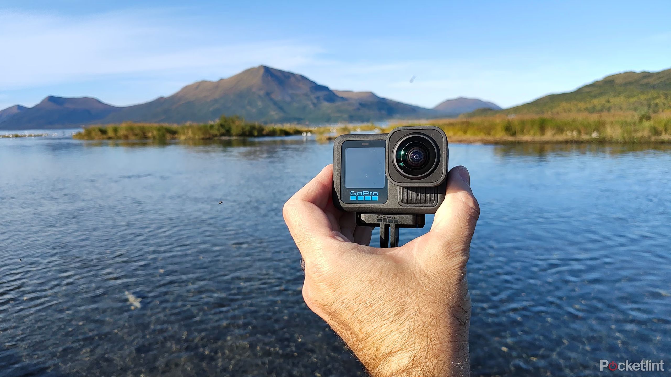 A person holding a GoProHERO13 Black in the Alaskan wilderness. 