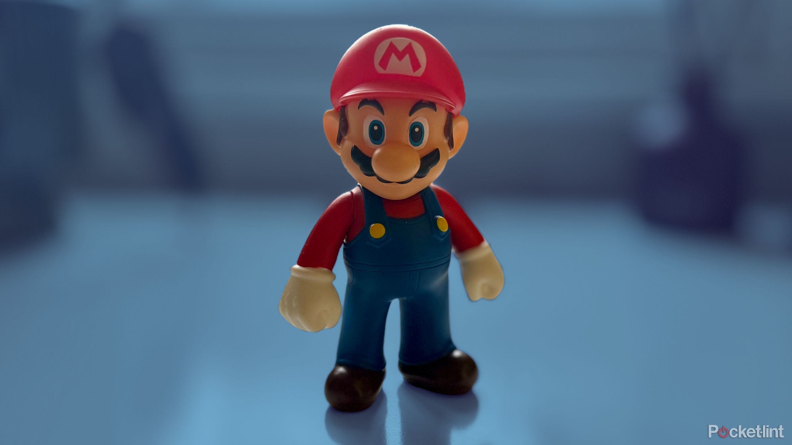 A Mario figure on a desk on a colored background