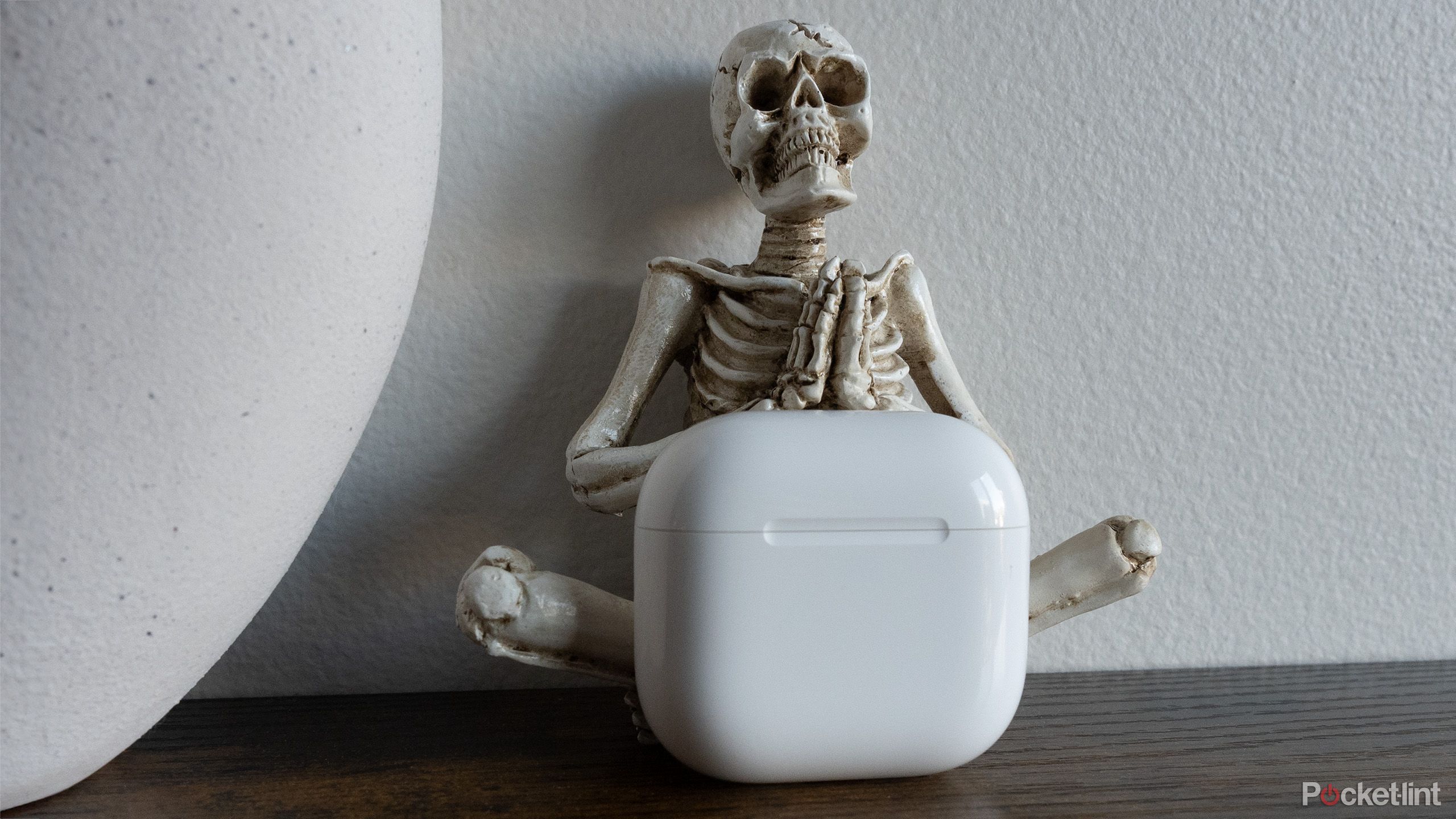 The AirPods 4's case on a table in front of a skeleton