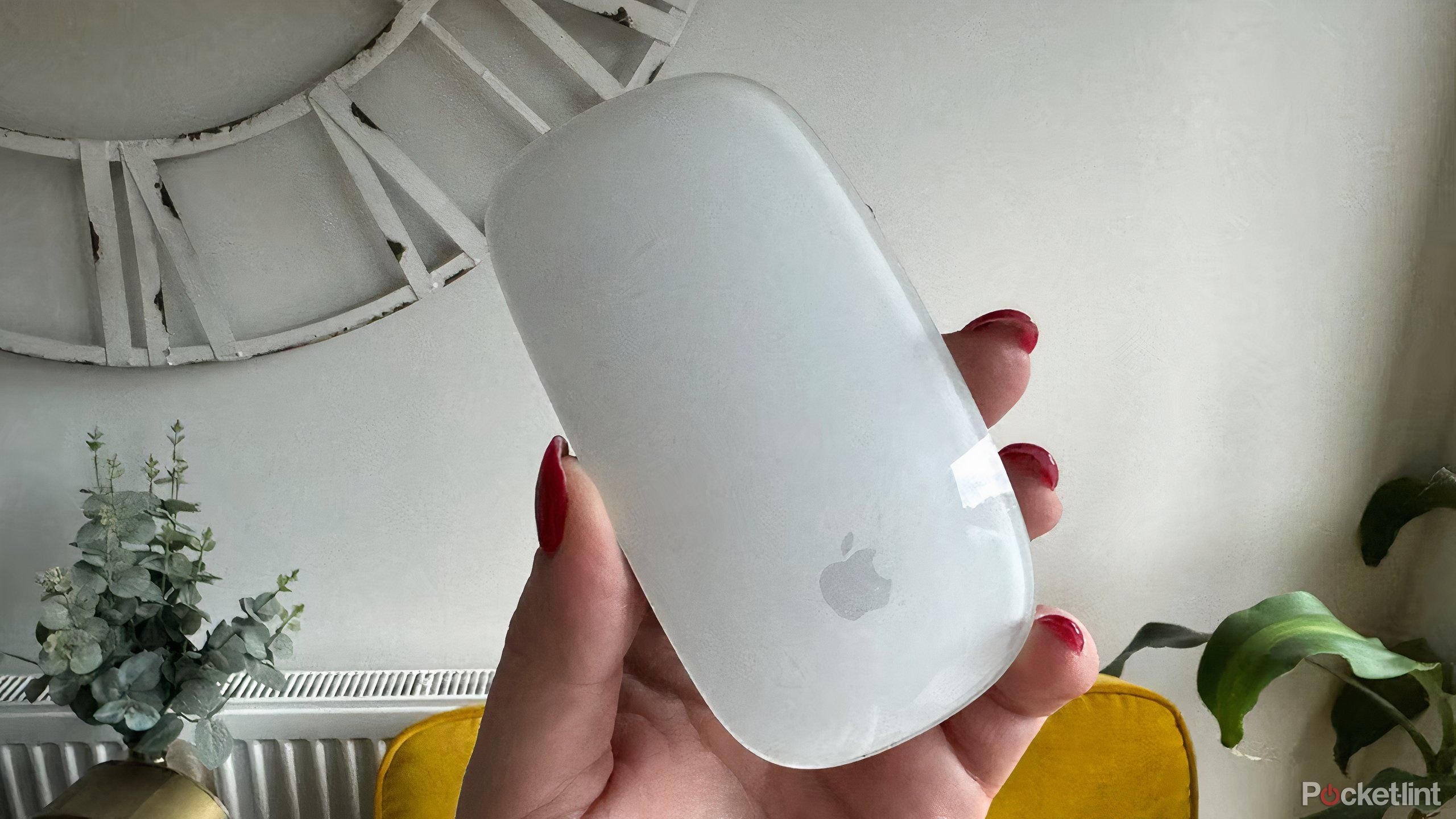 A hand holding a white Apple Magic Mouse.